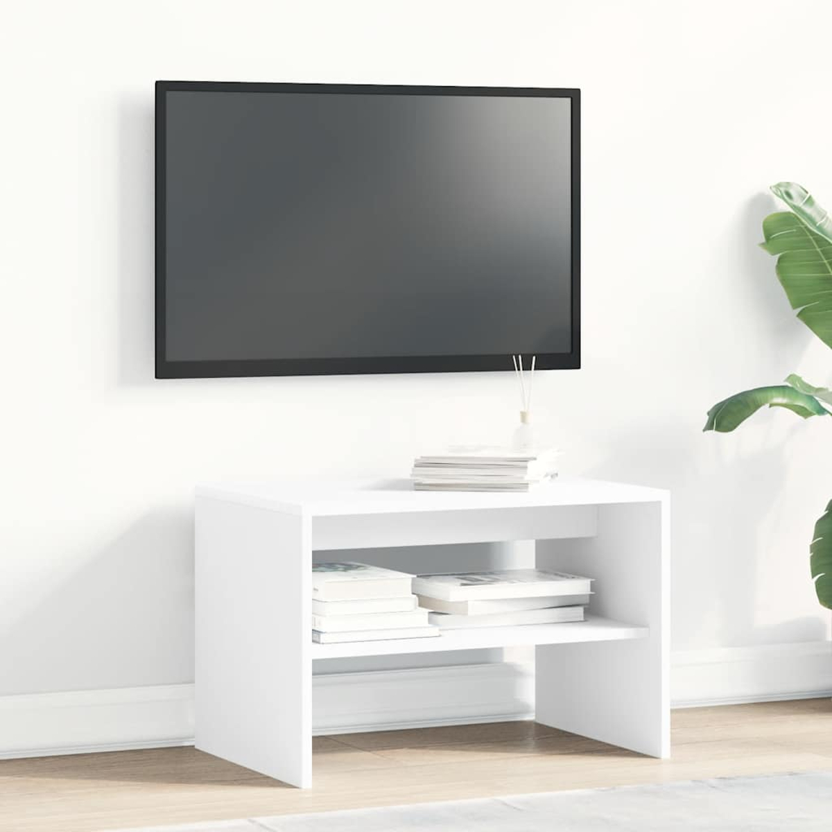 Un mueble de TV blanco contra una pared blanca con libros y una planta al lado, y un televisor colgado en la pared.