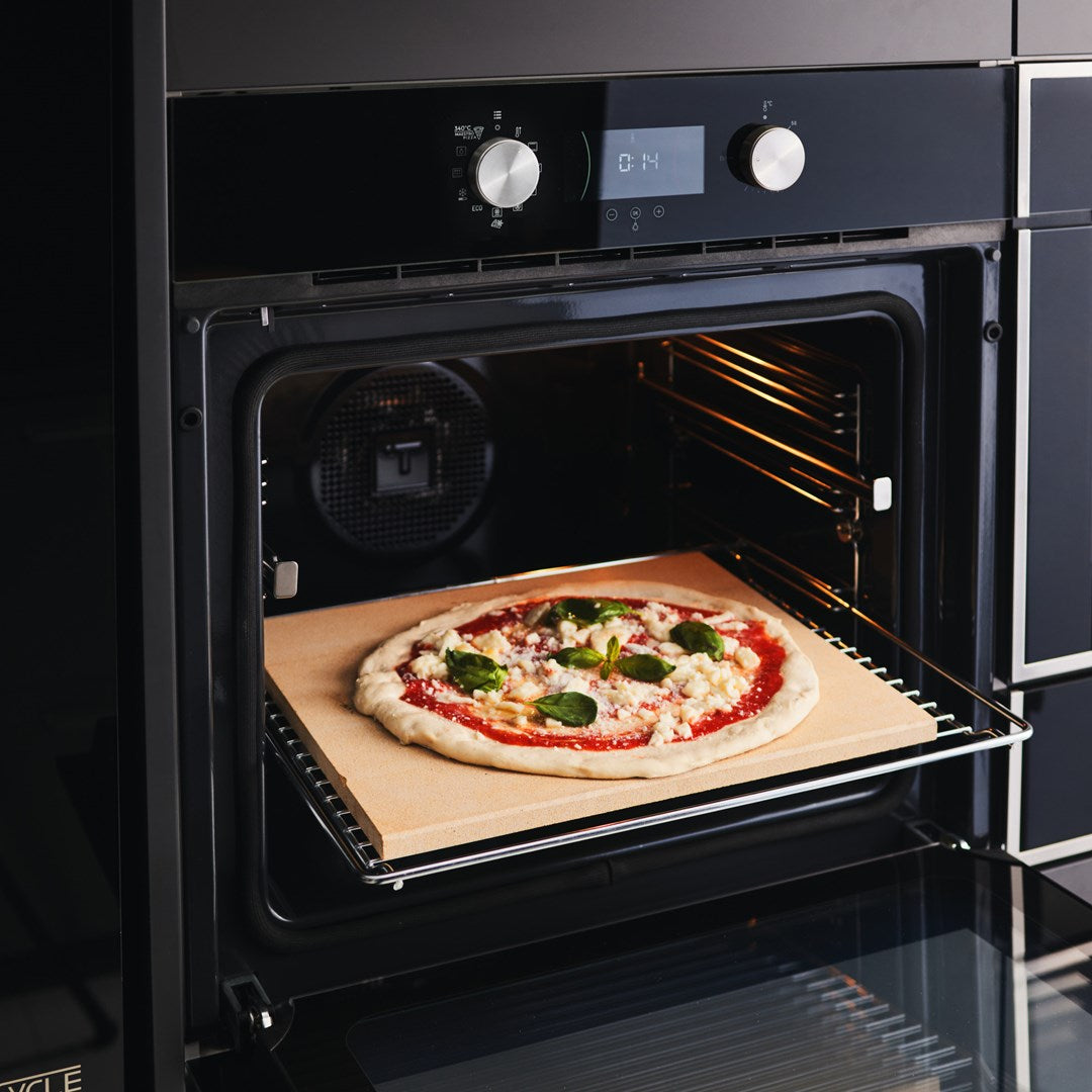 Una pizza fresca en una piedra de hornear dentro de un horno.