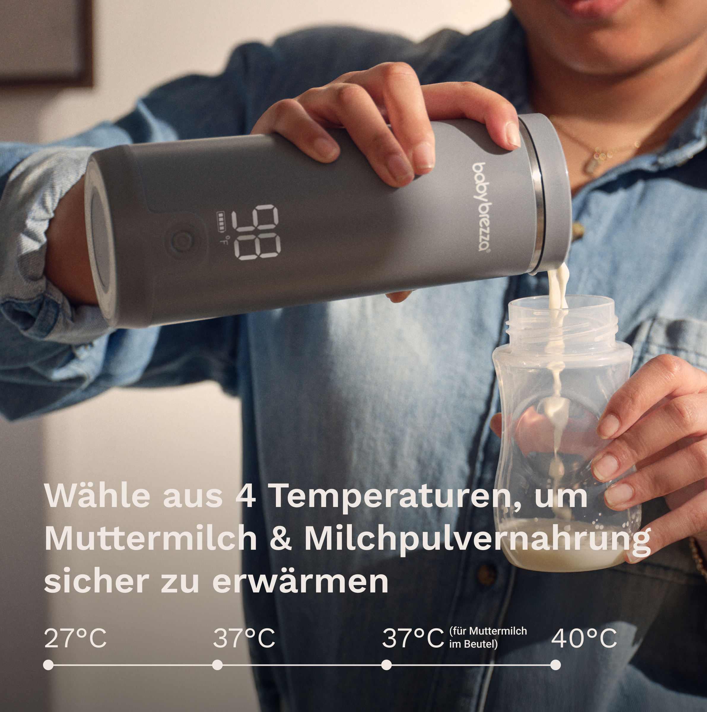 Eine Person gießt Milch aus einer grauen Baby Brezza Flasche in eine kleine Babyflasche.
