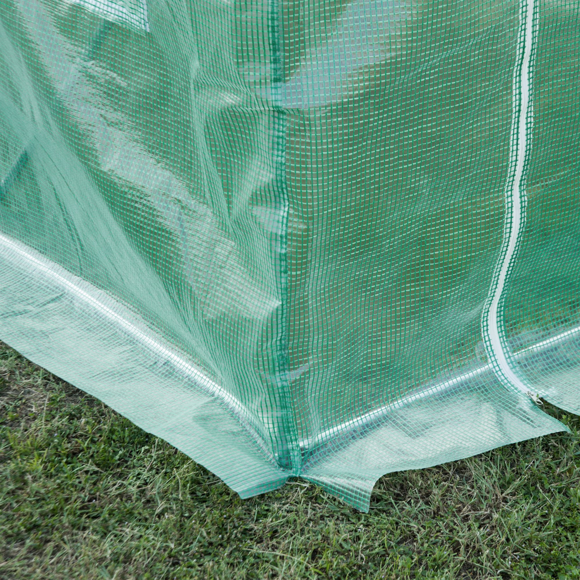 Primer plano del exterior de un invernadero de plástico verde con puerta blanca con cremallera.