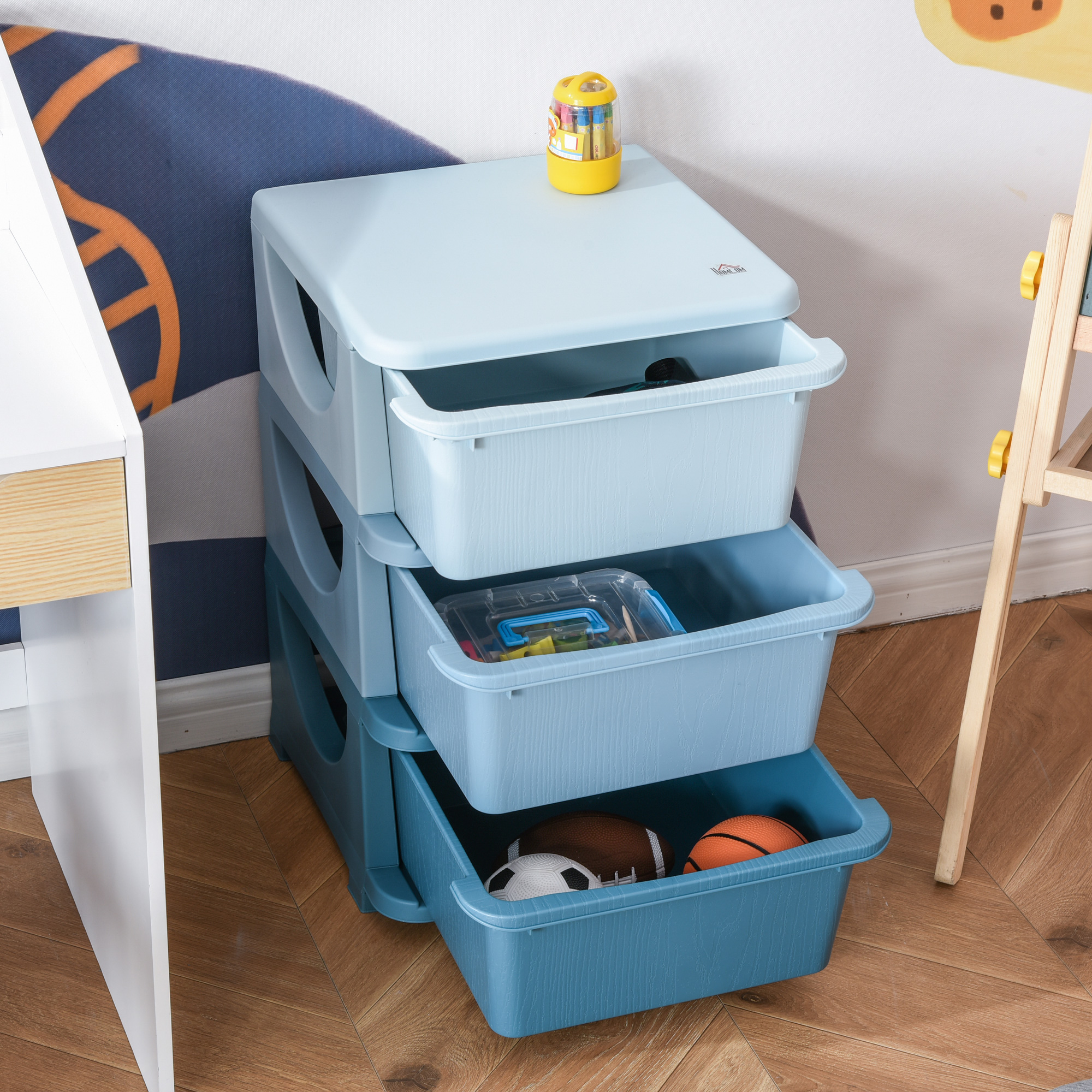 Una torre de almacenamiento de plástico azul con tres cajones llenos de juguetes sobre un suelo de madera.