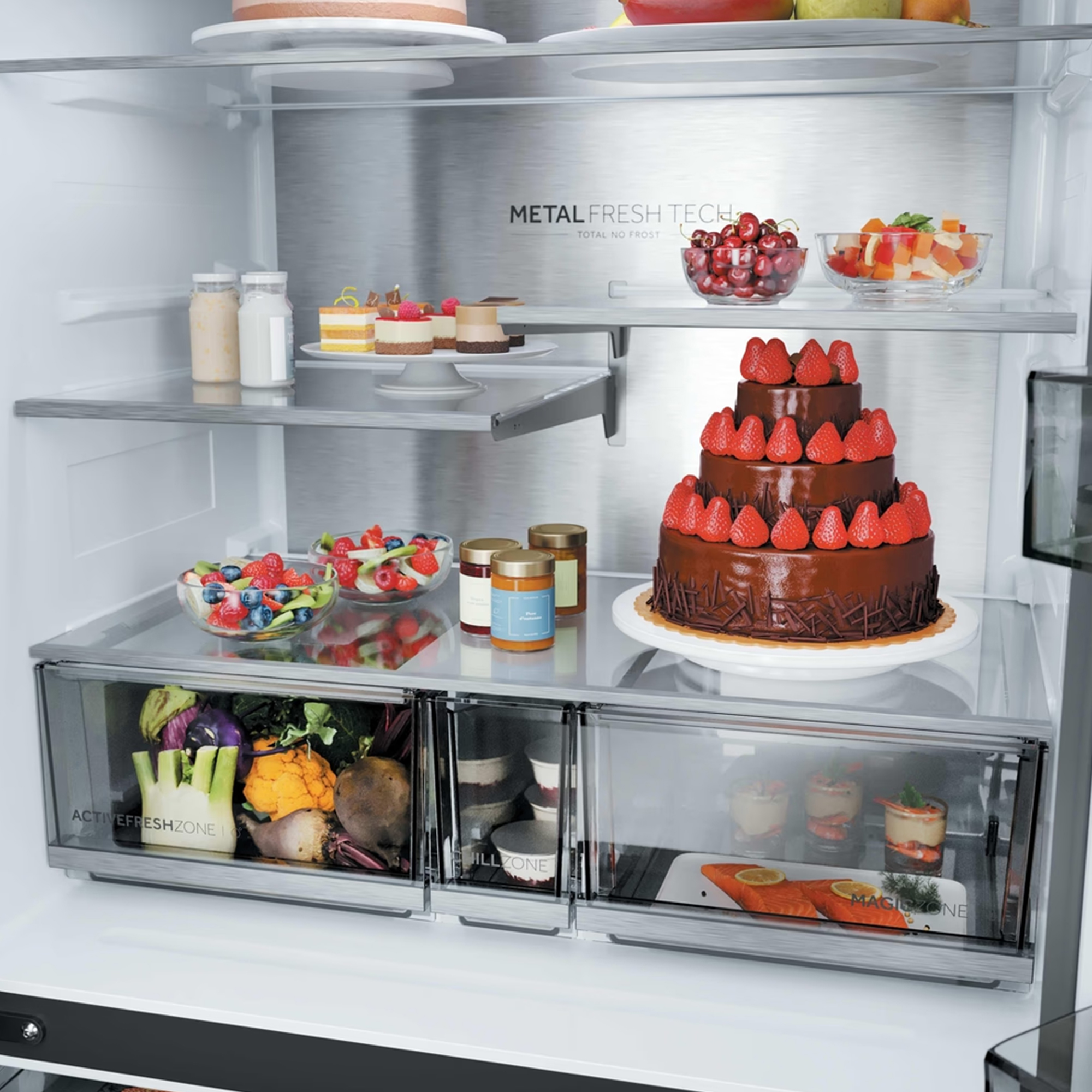 Refrigerador bien abastecido con fruta fresca, postres y un gran pastel de chocolate.