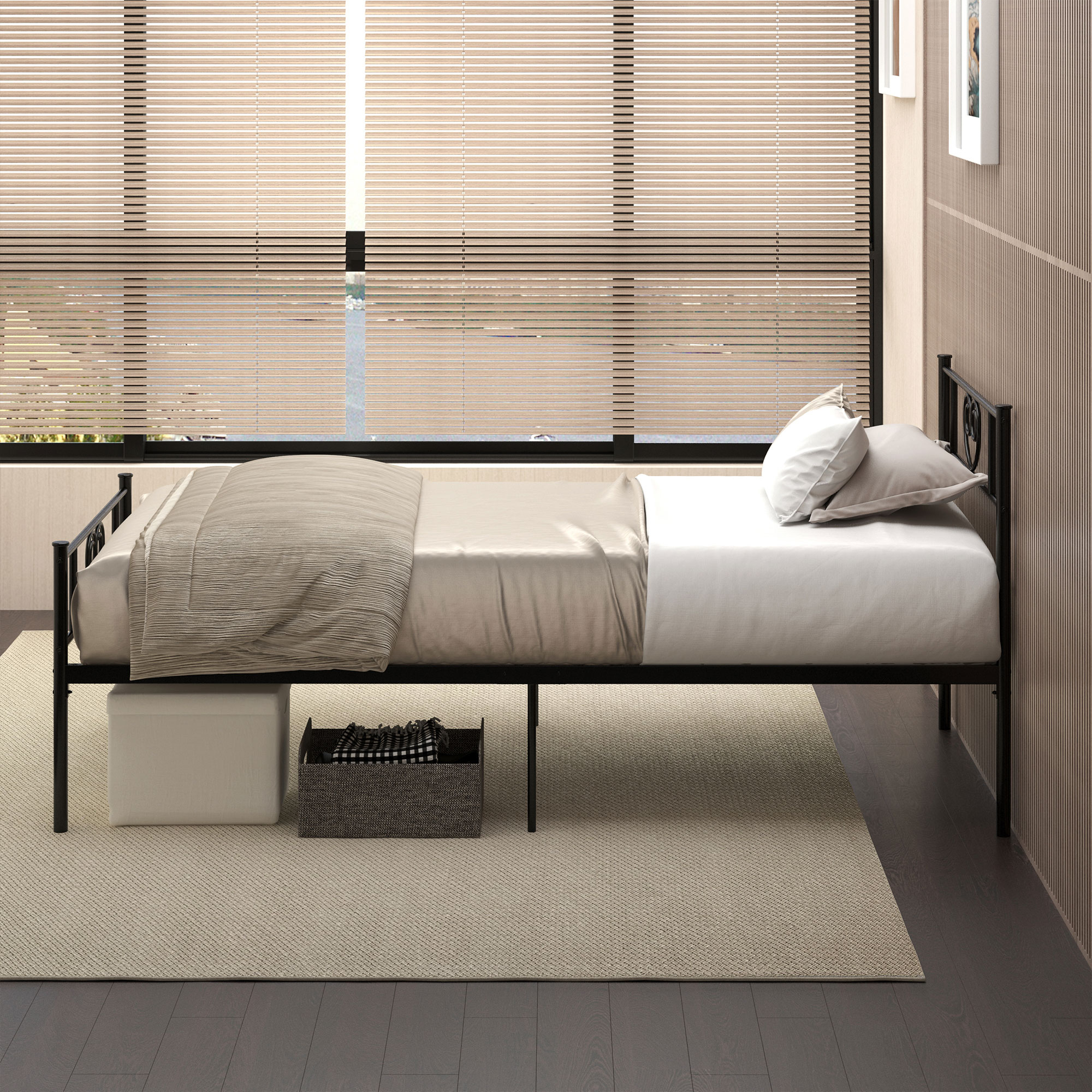 Una cama individual de metal negro con ropa de cama beige sobre una alfombra clara, en una habitación con grandes ventanales.