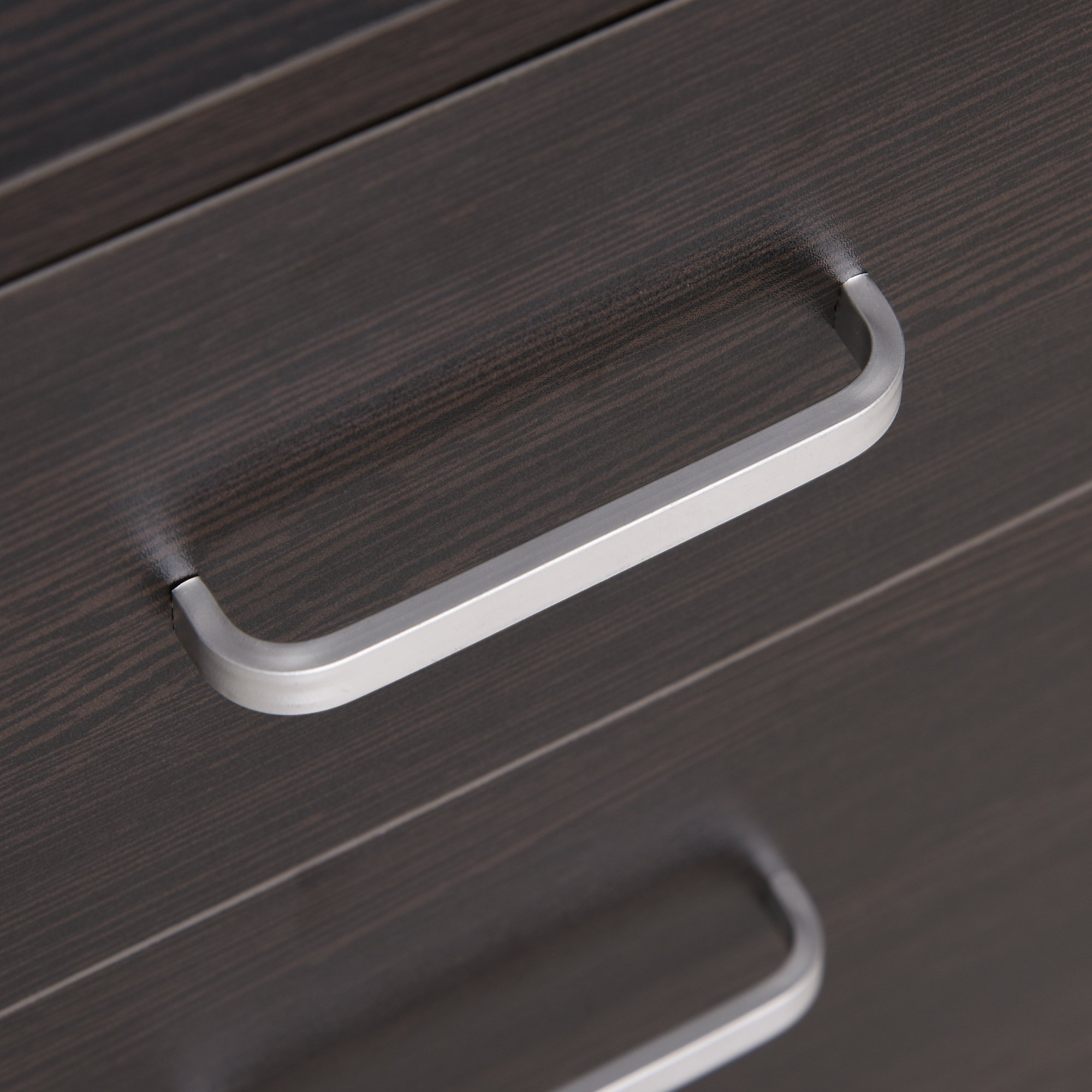 Primer plano de una cómoda de madera oscura con tiradores de plata cepillada.