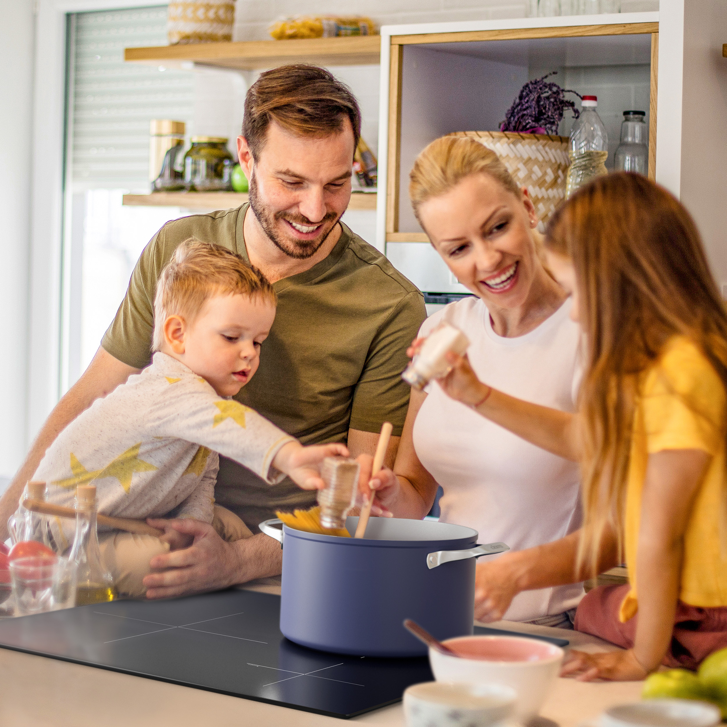 Una familia cocinando junta en una cocina luminosa alrededor de una olla.