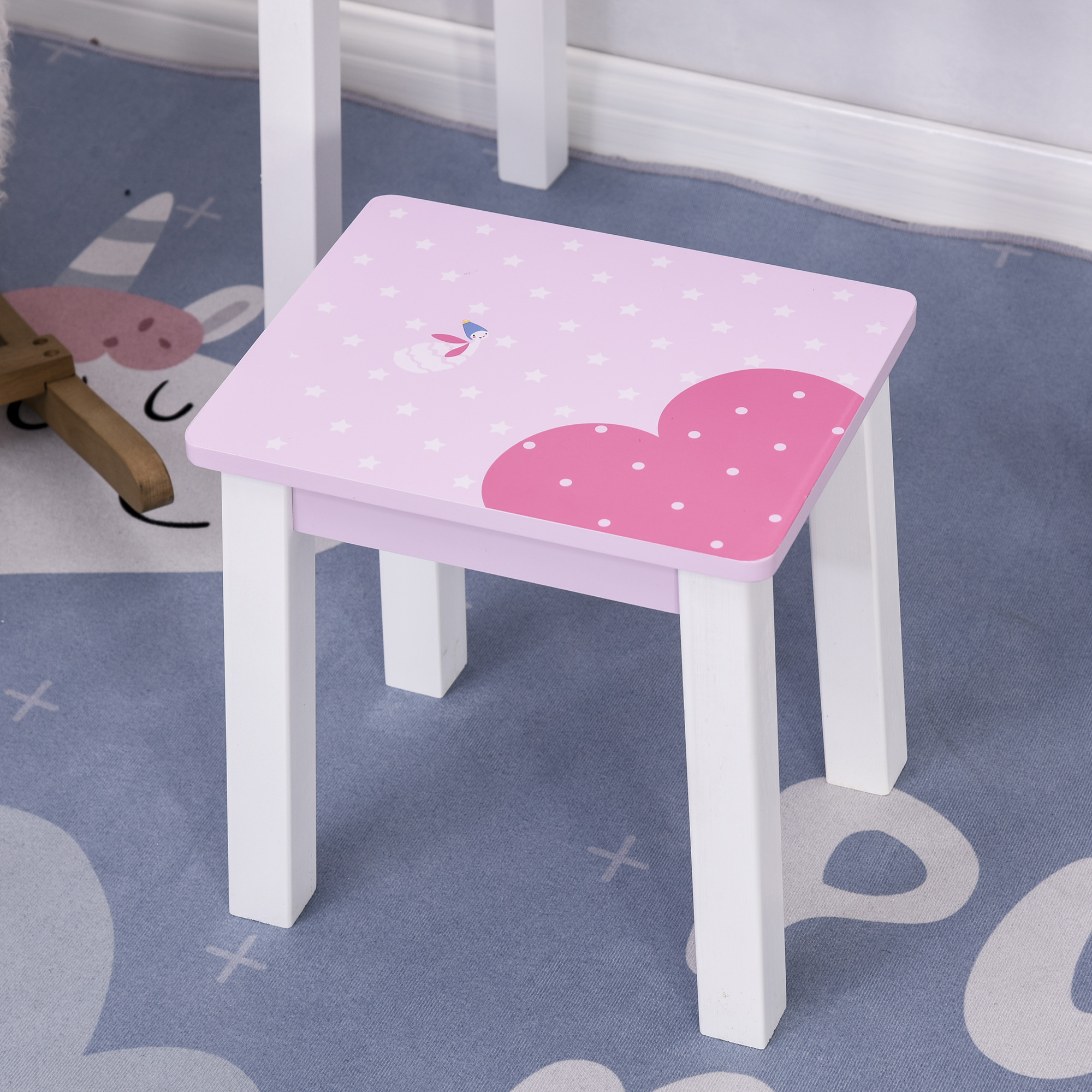Pequeño taburete de madera blanca con asiento rosa de estrellas y corazones sobre una alfombra azul.
