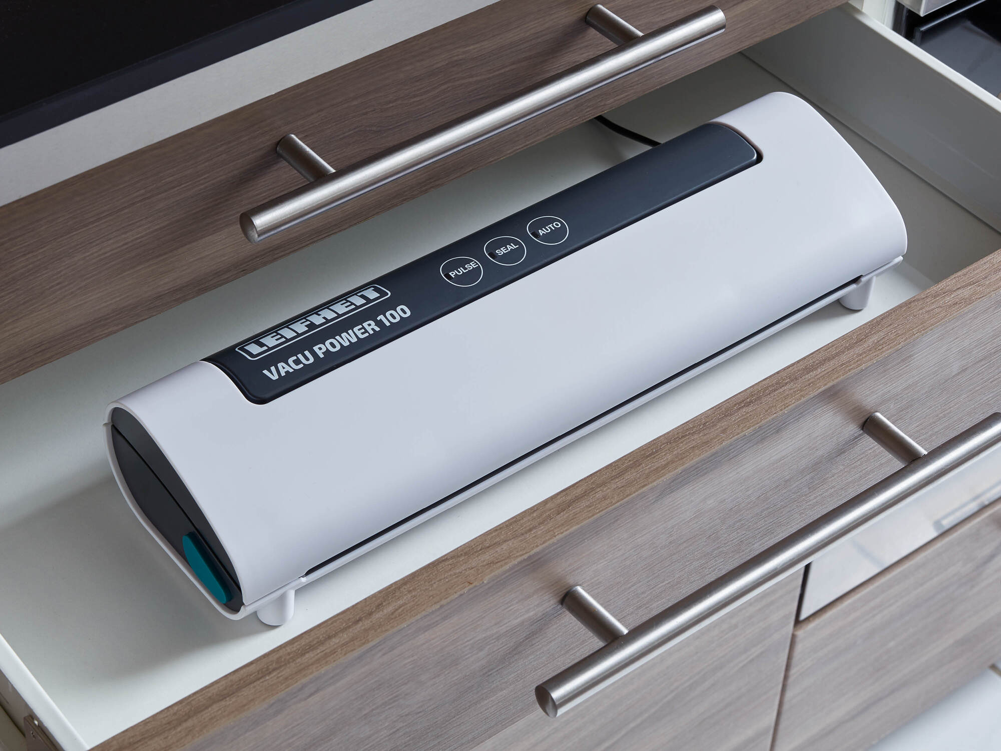 Una macchina sottovuoto Leifheit Vacu Power 100 è riposta in un cassetto di legno.