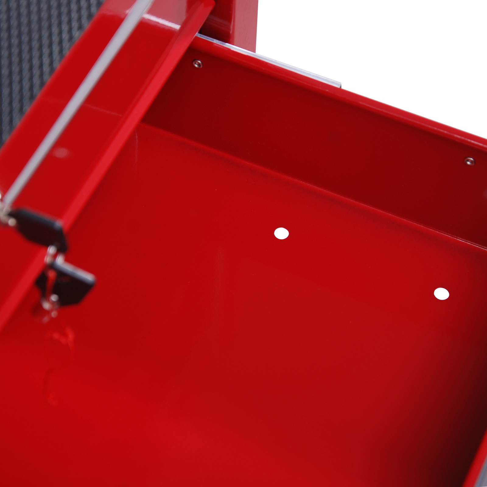 Un cajón de caja de herramientas de metal rojo abierto con dos pequeños agujeros en el fondo sobre fondo blanco.
