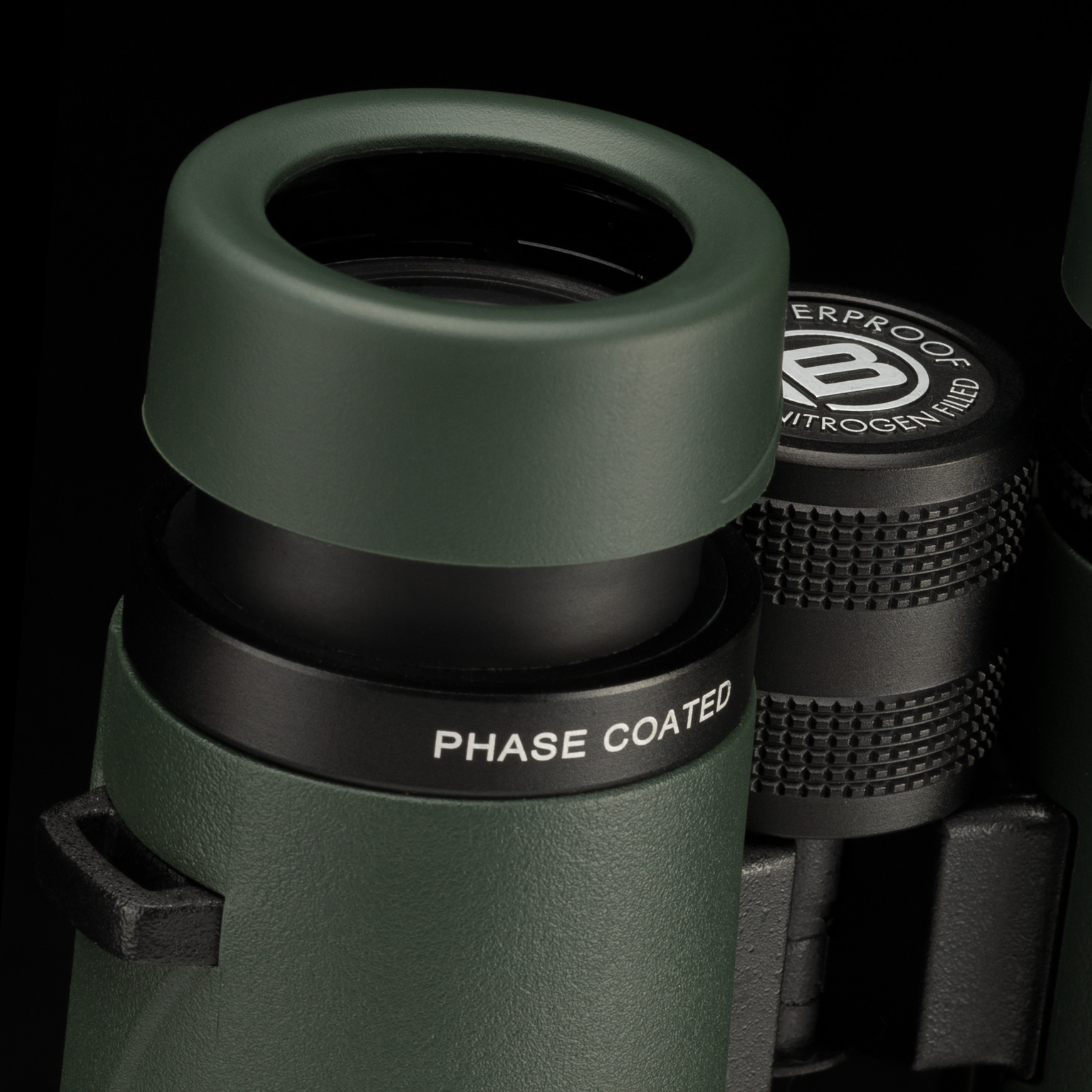 Primer plano de binoculares verdes con texto Phase Coated en el cilindro de la lente.