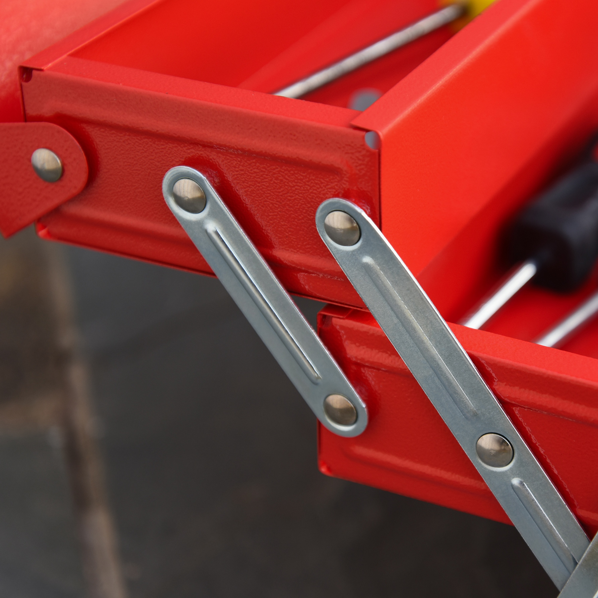 Primer plano de una caja de herramientas metálica roja abierta con bisagras plateadas.