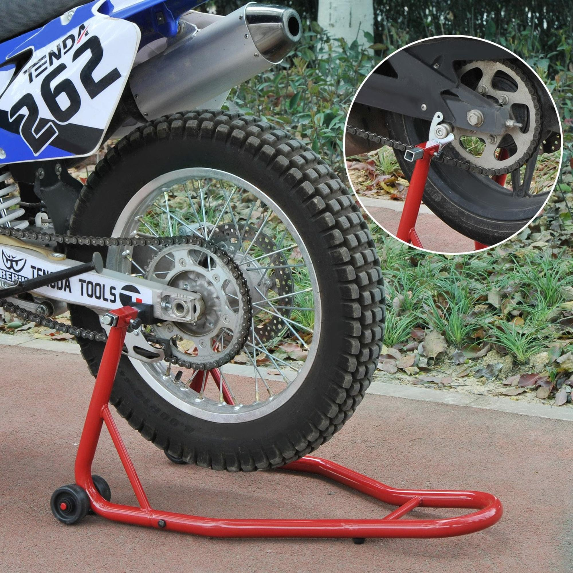 La rueda trasera de una moto de cross se eleva del suelo con un soporte rojo.