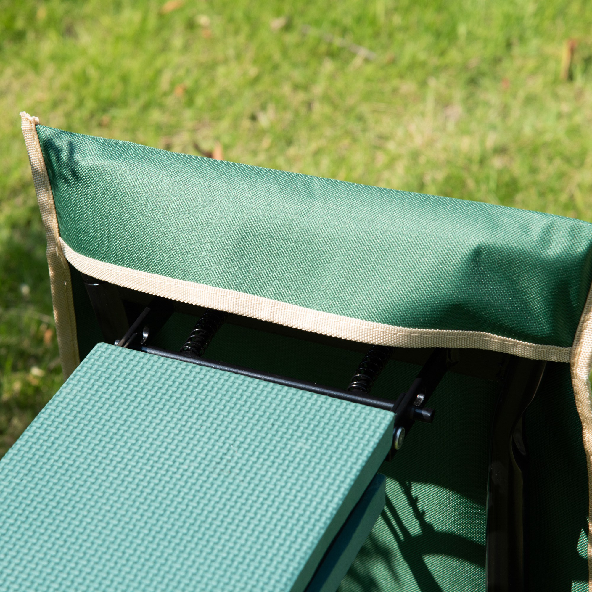 Silla de camping plegable verde sobre césped con estructura metálica visible.
