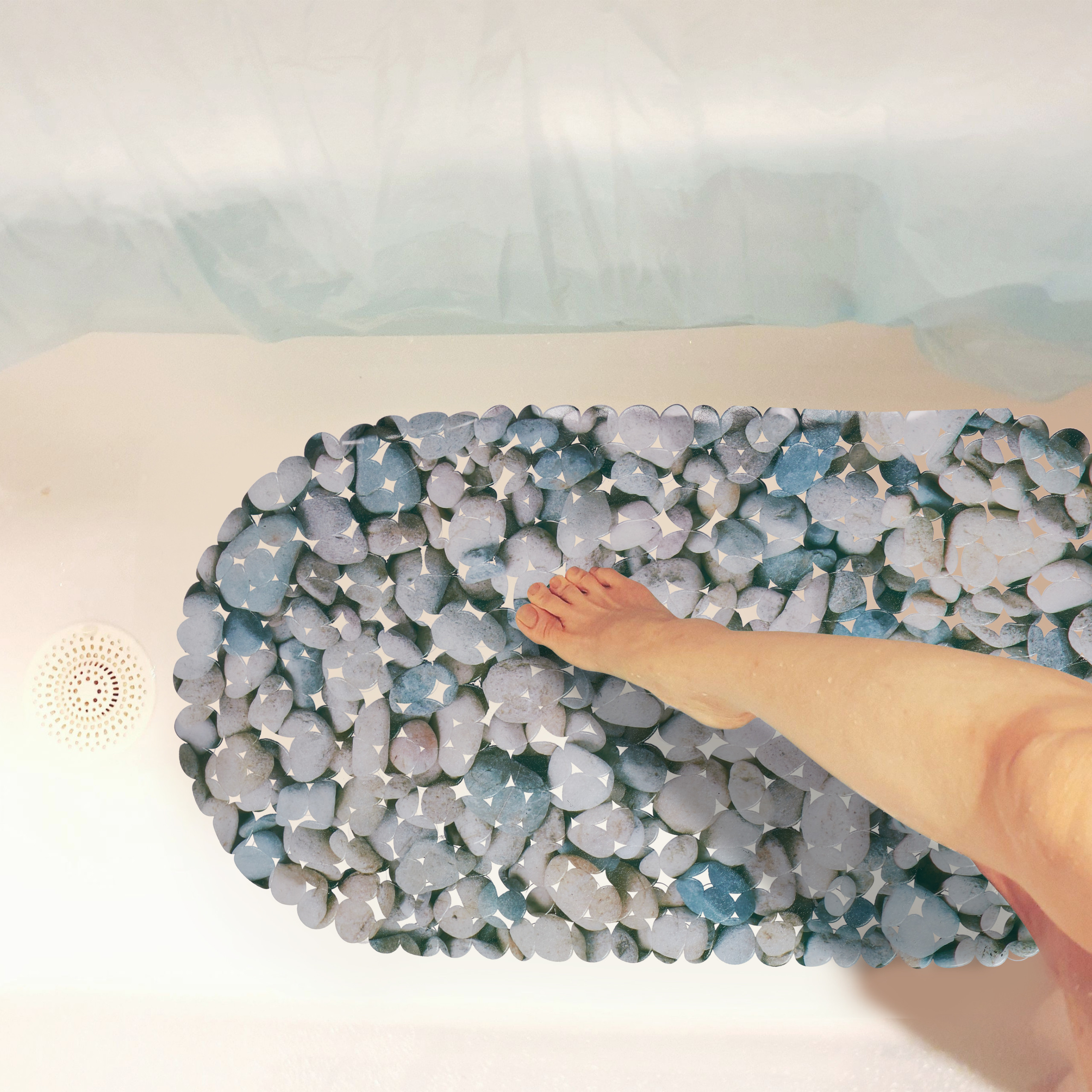 Ein Fuß steht auf einer steinmusterierten Badematte in einer weißen Badewanne mit weißem Abfluss.