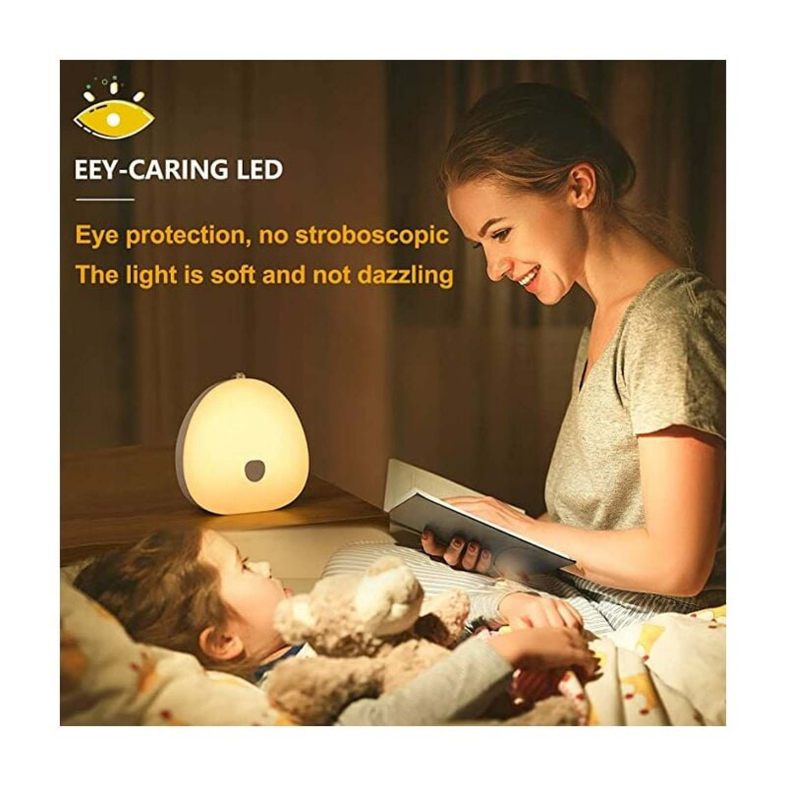 Eine Frau liest einem Kind im Bett mit einem runden LED-Nachtlicht ein Buch vor.