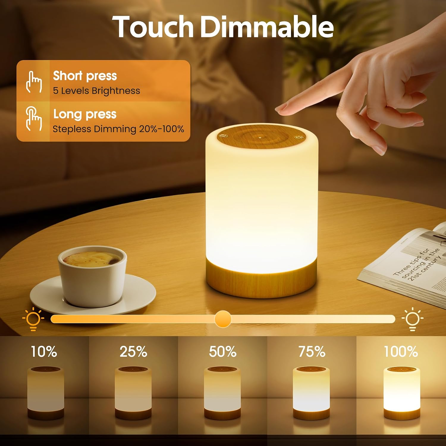Eine Hand berührt eine zylindrische, berührungsdimmbare Lampe auf einem Holztisch mit Kaffeetasse und Buch.