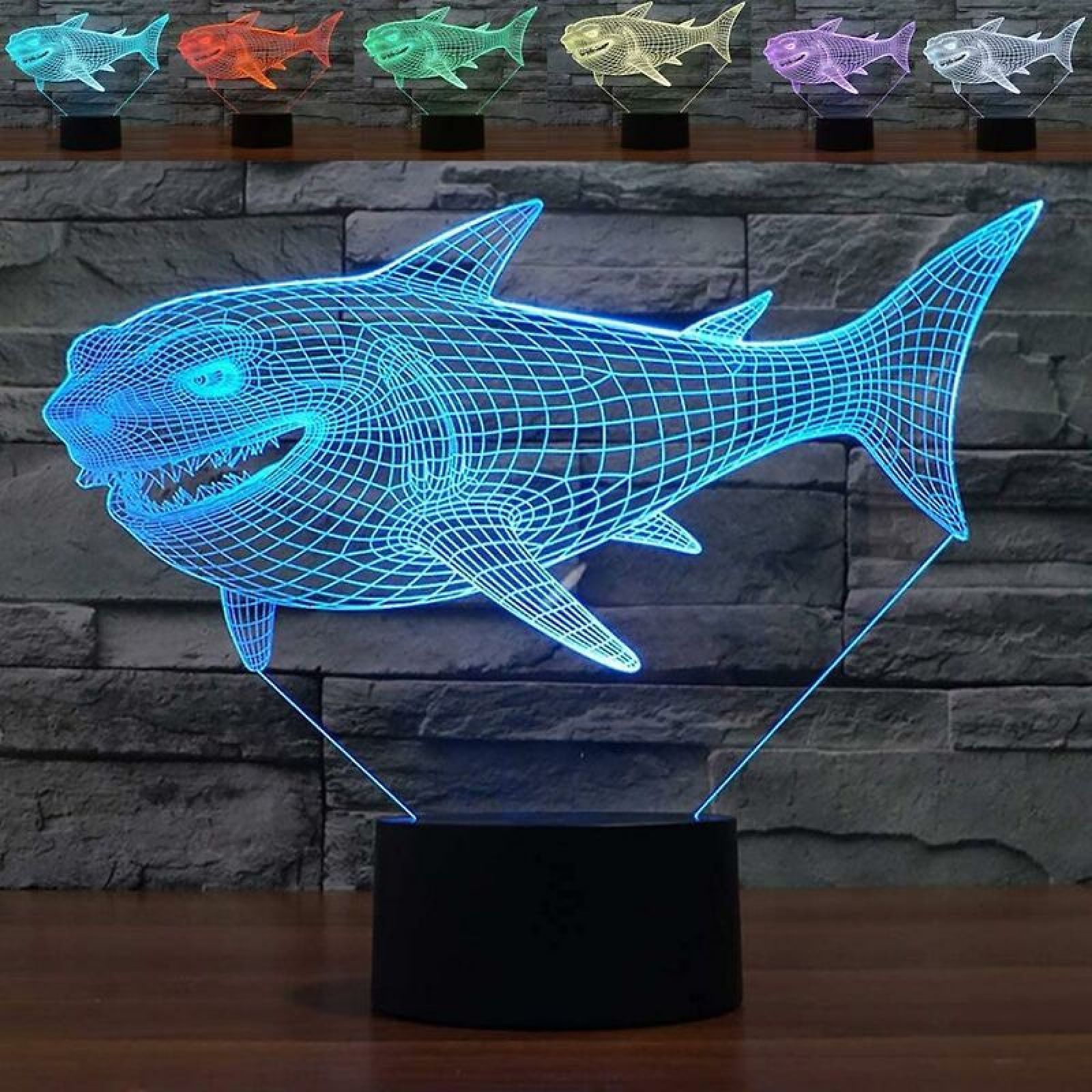 Eine blaue 3D-Haifischlampe auf einem Holztisch vor einer Steinwand; oben sind weitere Farboptionen zu sehen.