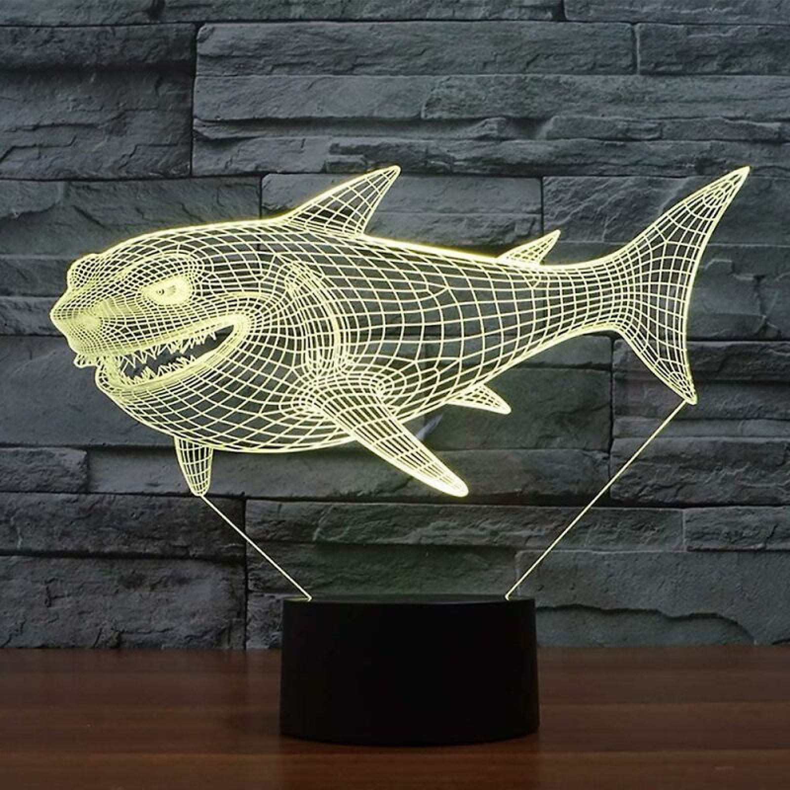 Eine Leuchtschlampe in Haiform auf einem Sockel vor einer grauen Steinwand.