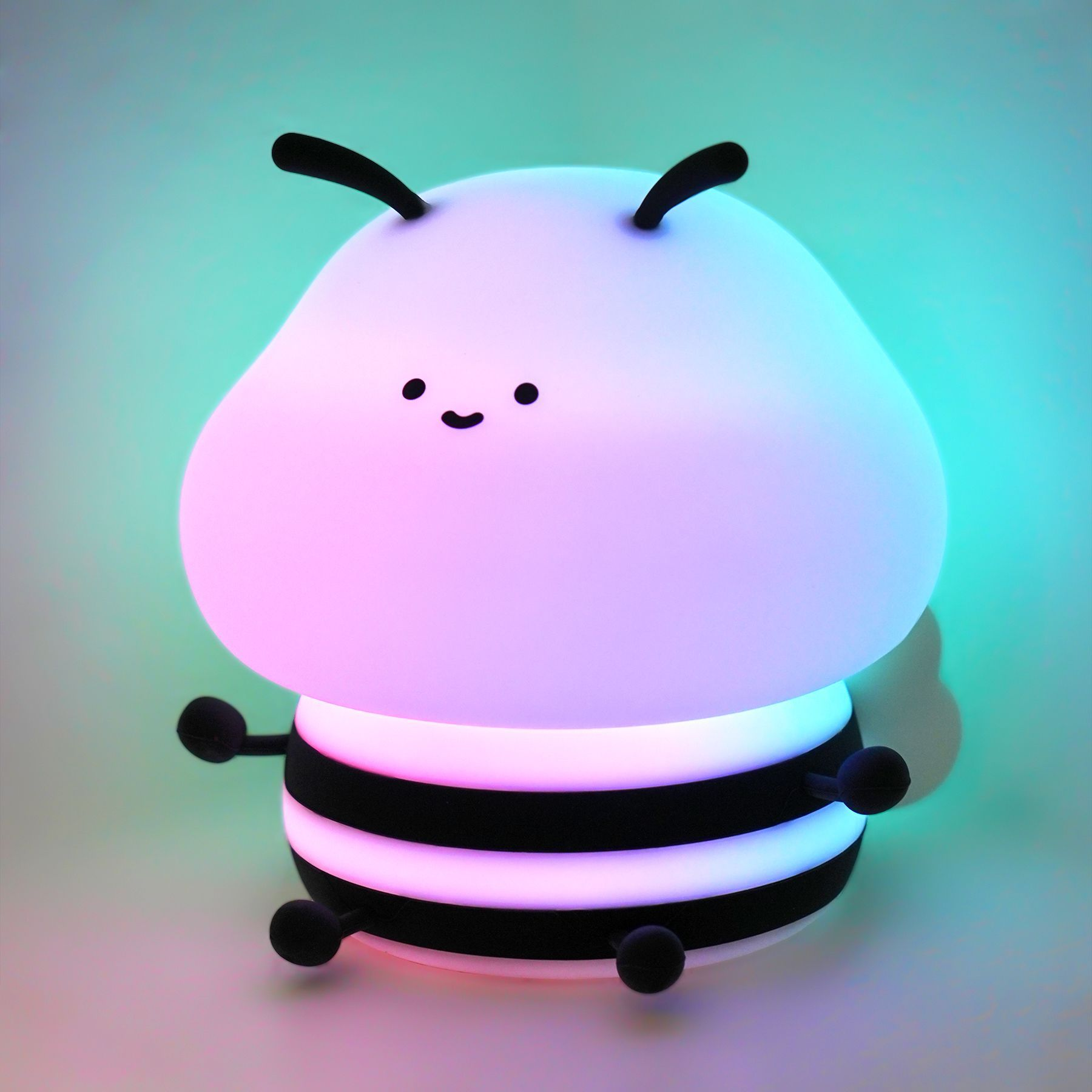 Eine süße, leuchtende Bienenlampe mit rosa und blauen Lichtern vor einem türkisfarbenen Hintergrund.