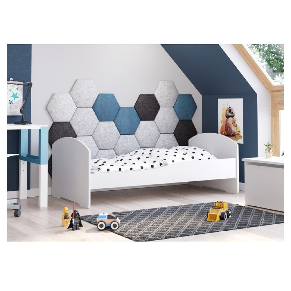 Ein weißes Kinderbett mit blauen und grauen Wandpaneelen, Spielzeug auf einem gemusterten Teppich im Dachzimmer.