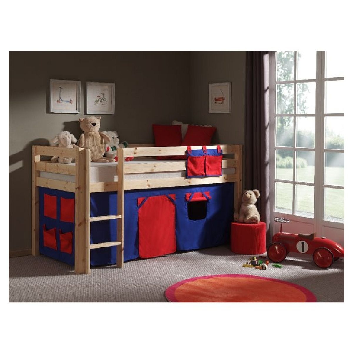 Ein Kinderzimmer mit einem Holzhochbett mit blauen und roten Stoffen, Teddys, einem roten Spielzeugauto und großem Fenster.