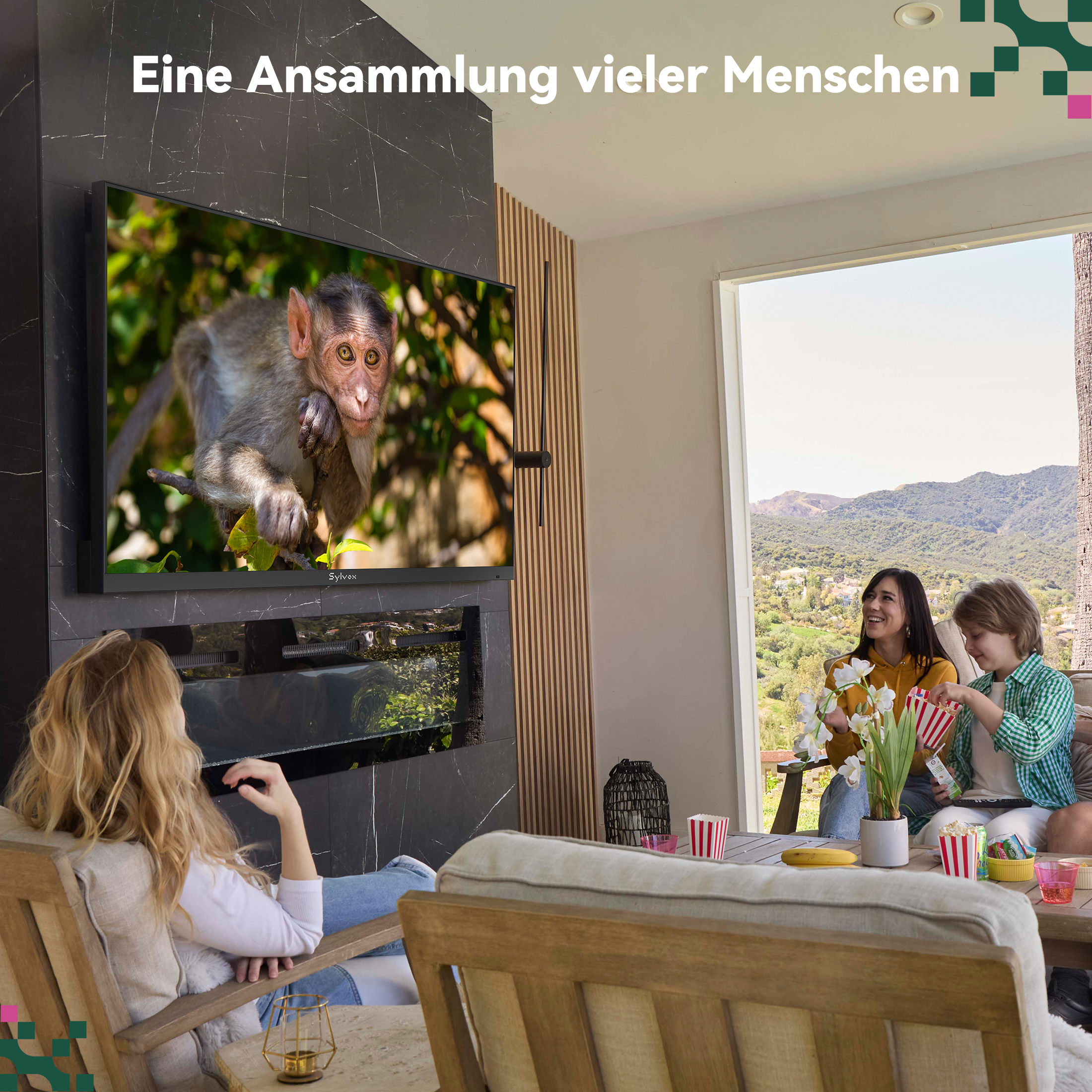 Personas se relajan en una sala luminosa viendo un mono en un gran televisor con vistas a la montaña.