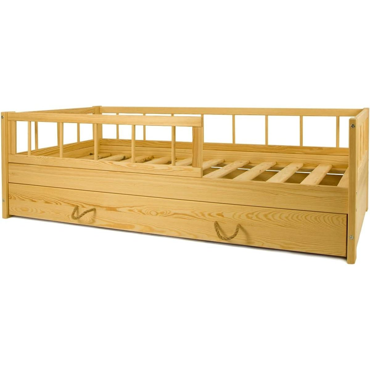 Ein hölzernes Kinderbett mit Schutzgitter und einer großen Schublade darunter.