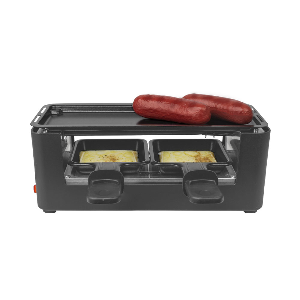 Una raclette da tavolo nera con due salsicce sopra e due padellini che sciolgono il formaggio sotto.