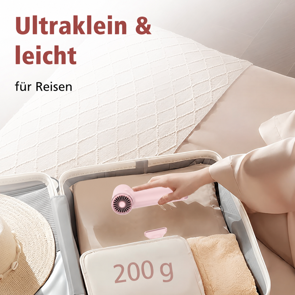 Eine Hand packt einen kleinen rosa Haartrockner in einen Koffer, mit Text auf dem Bild.