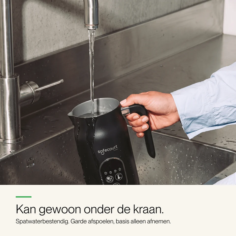 L'eau coule d'un robinet dans un mousseur à lait noir dans un évier en acier inoxydable.