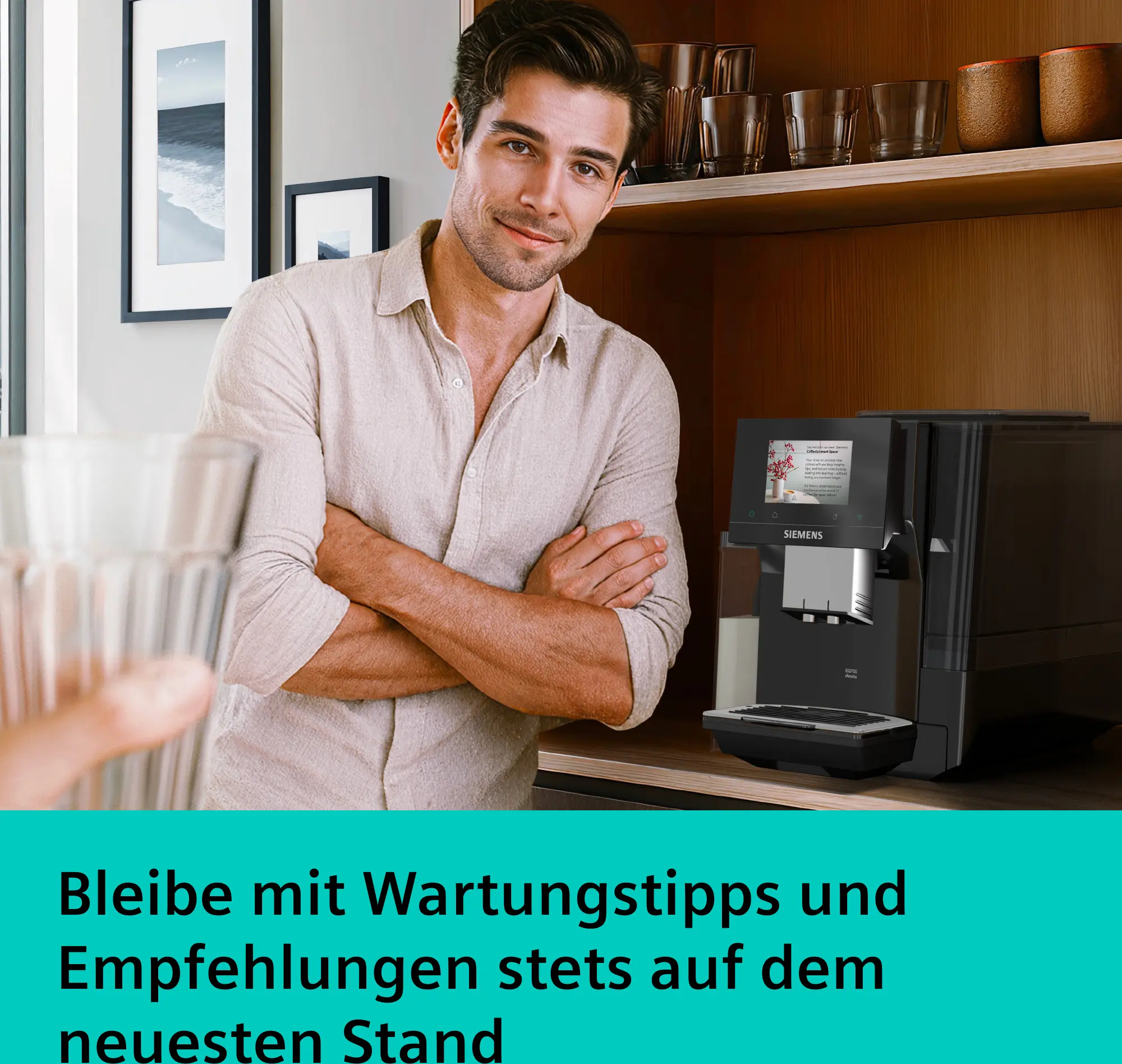 Un uomo sorridente in cucina accanto a una macchina da caffè Siemens, con un bicchiere in primo piano.