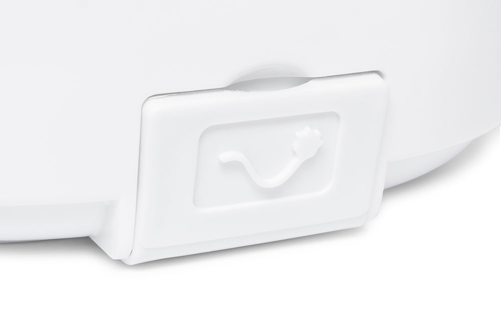 Nahaufnahme einer weißen Plastikabdeckung mit einem geprägten Kabelsymbol auf einer weißen Oberfläche.