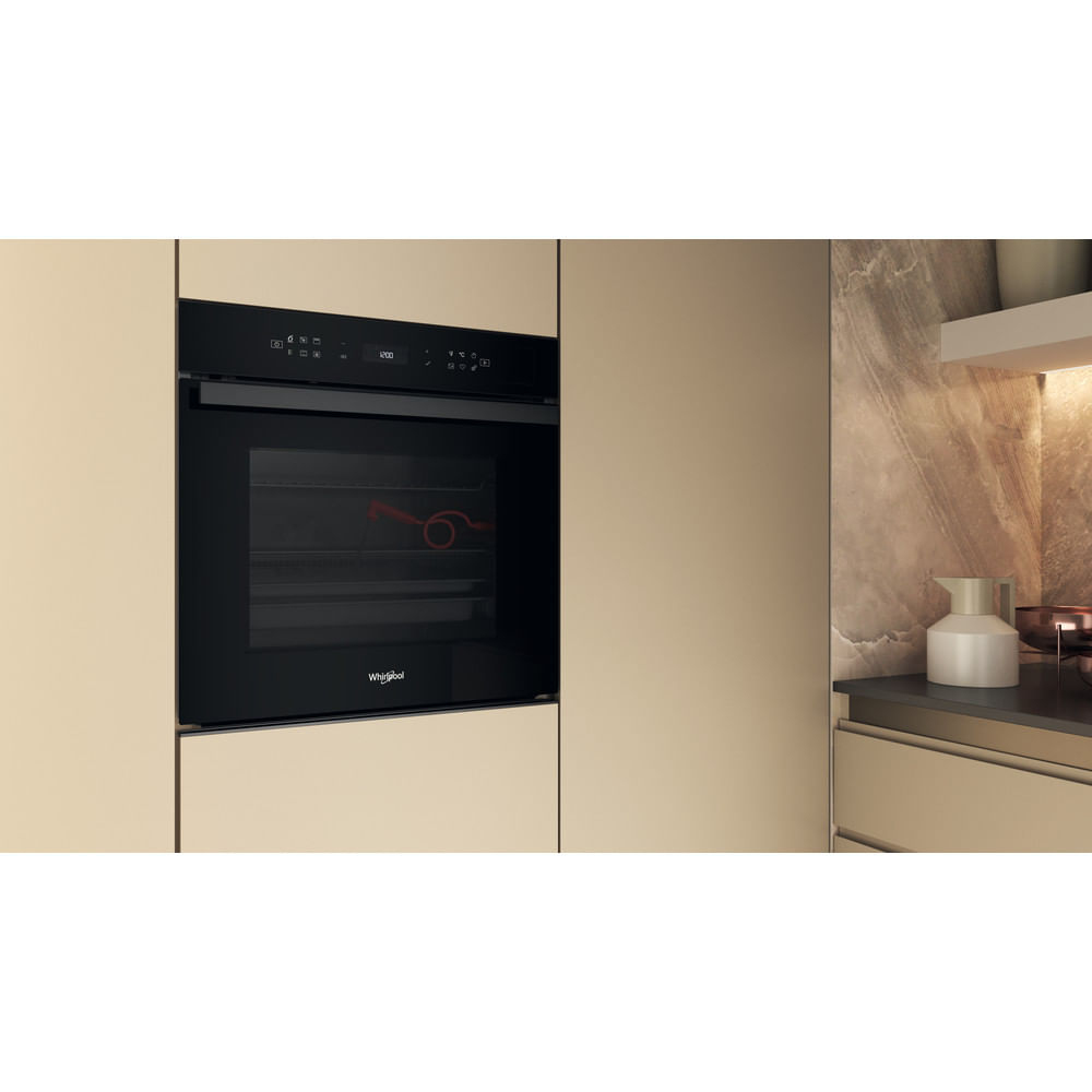Un horno empotrable negro con pantalla digital está integrado en una cocina moderna con gabinetes beige claro.