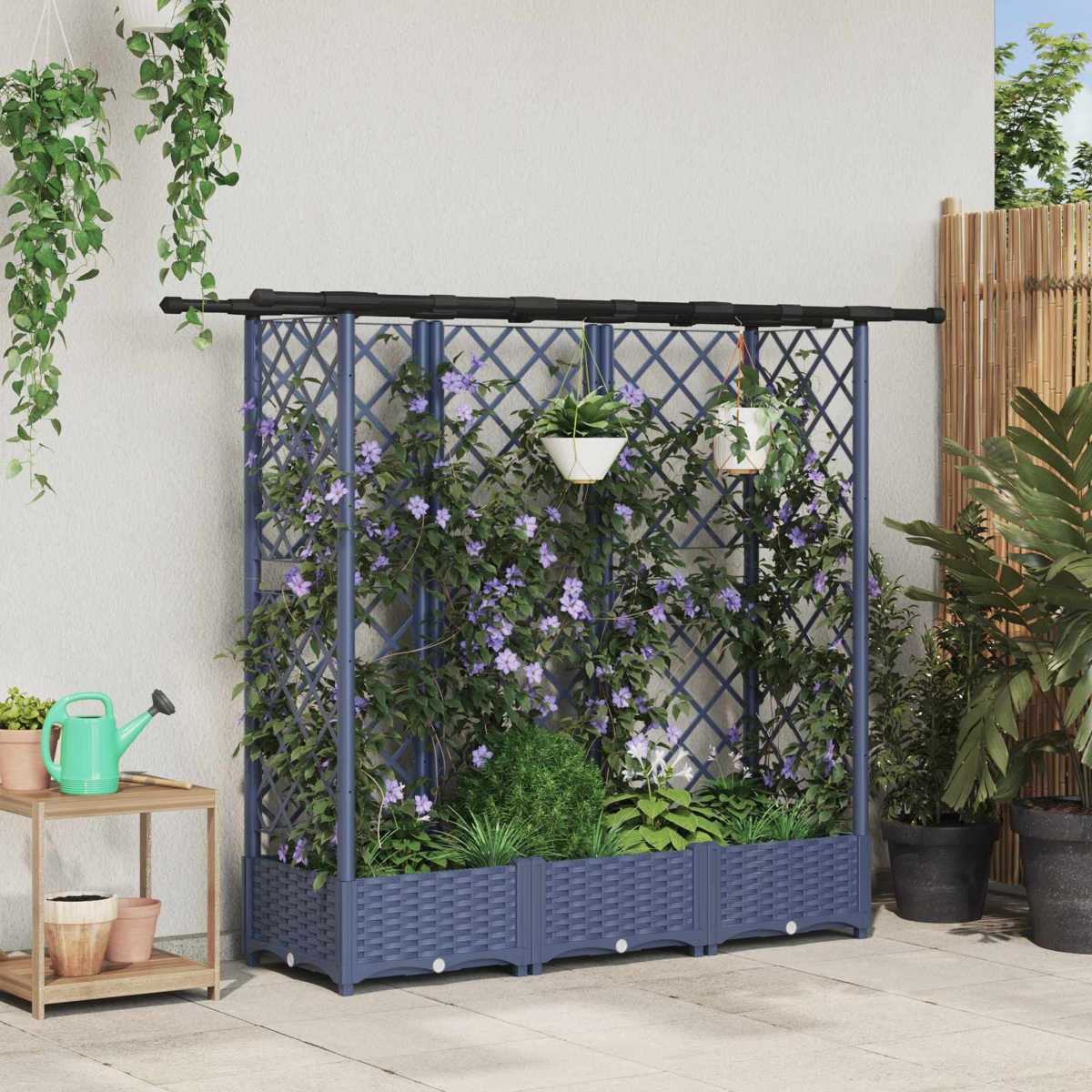 Ein blaues Rankgitter mit Pflanzkasten und violetten Kletterpflanzen auf einer Terrasse mit Hängetöpfen.