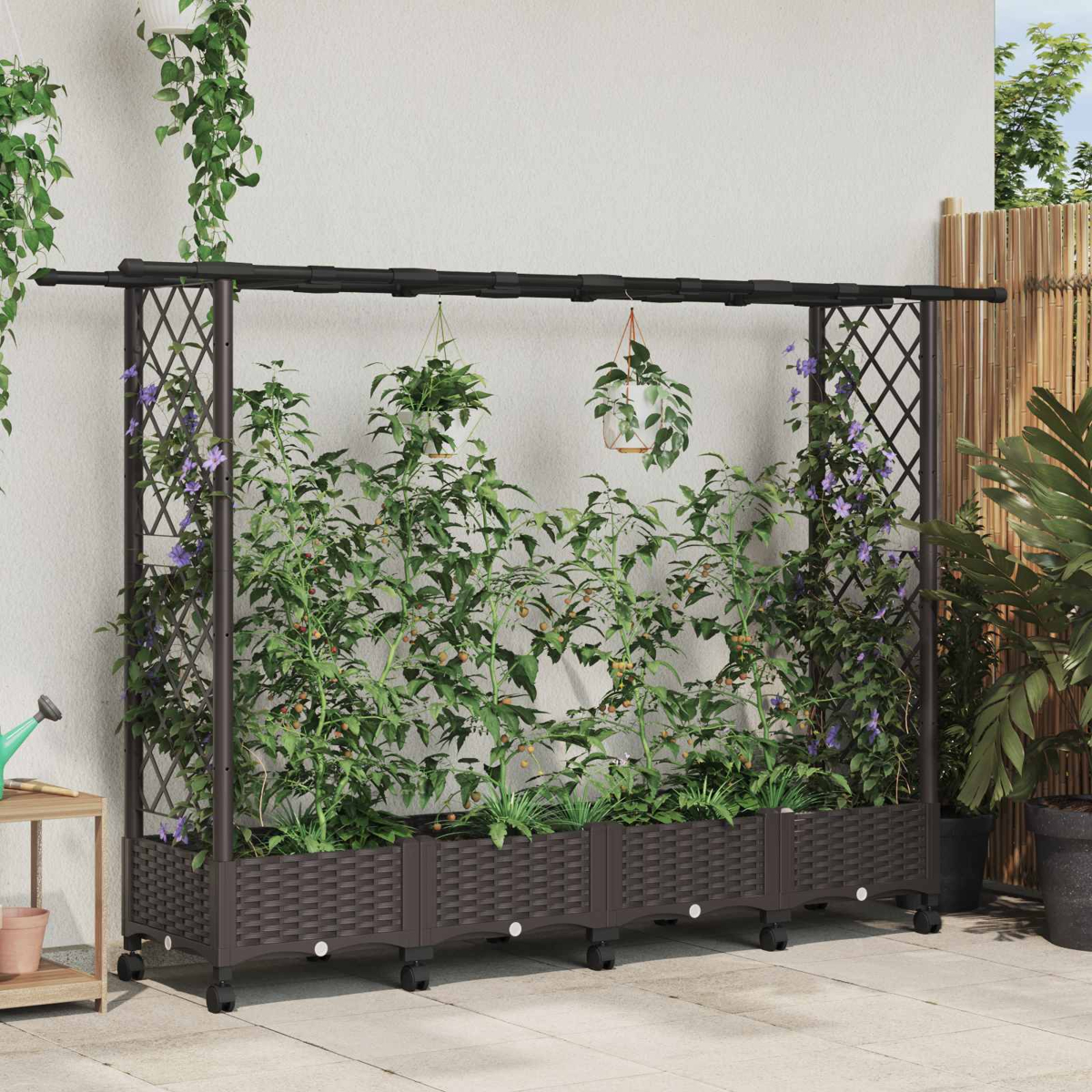Ein braunes Hochbeet aus Rattan mit schwarzem Metallspalier stützt Kletterpflanzen, H Töpfe und eine weiße Wand.