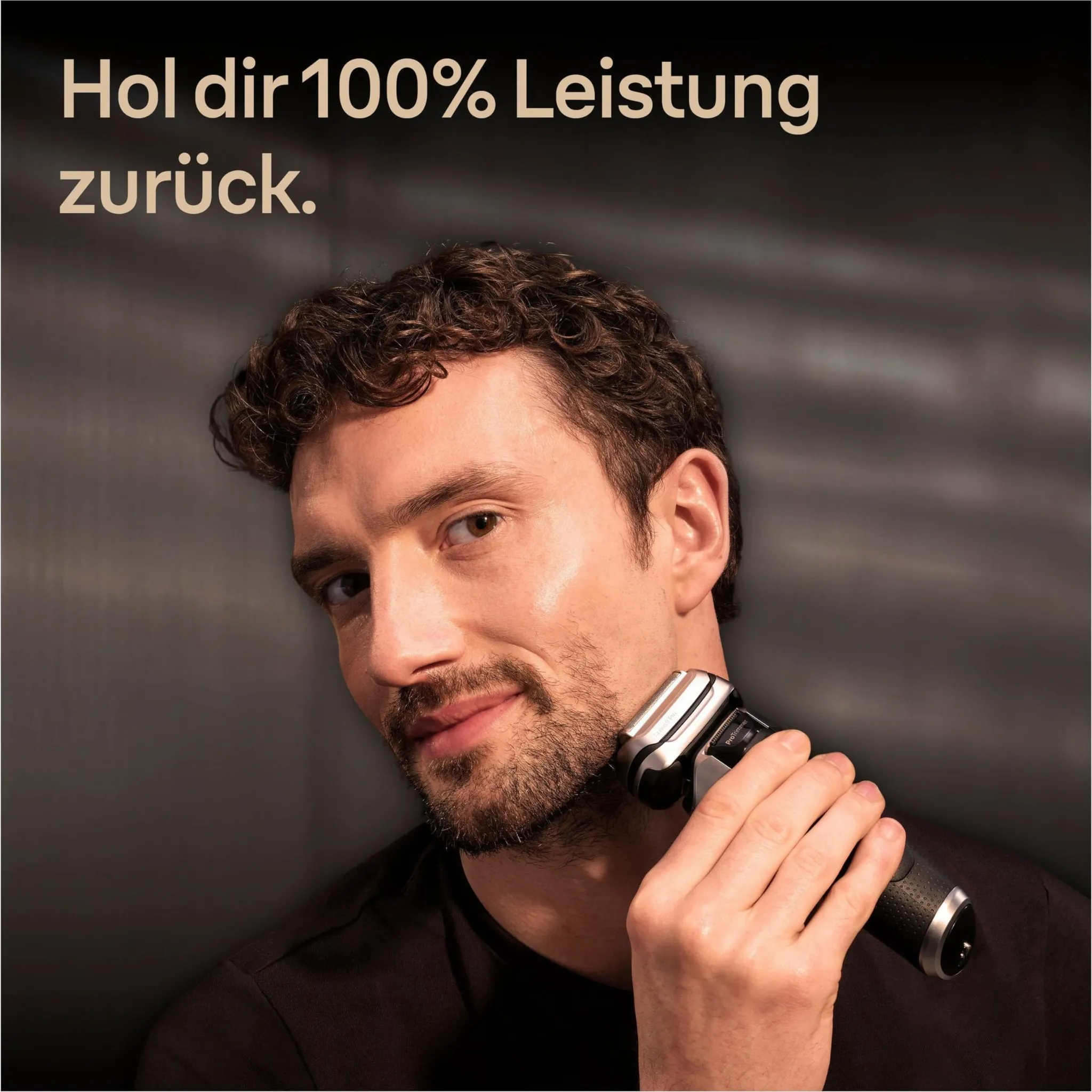 Ein Mann rasiert sich im Bad mit einem Elektierrasierer vor dunklem Hintergrund.