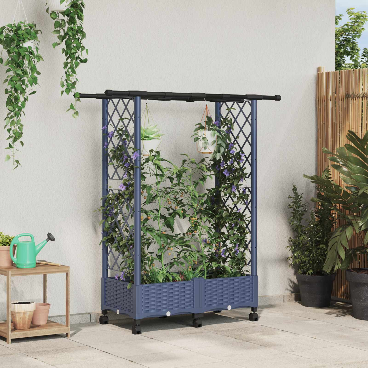 Ein blauer Rankkasten mit Tomatenpflanzen und Blumen auf einer Terrasse mit Hängetöpfen.