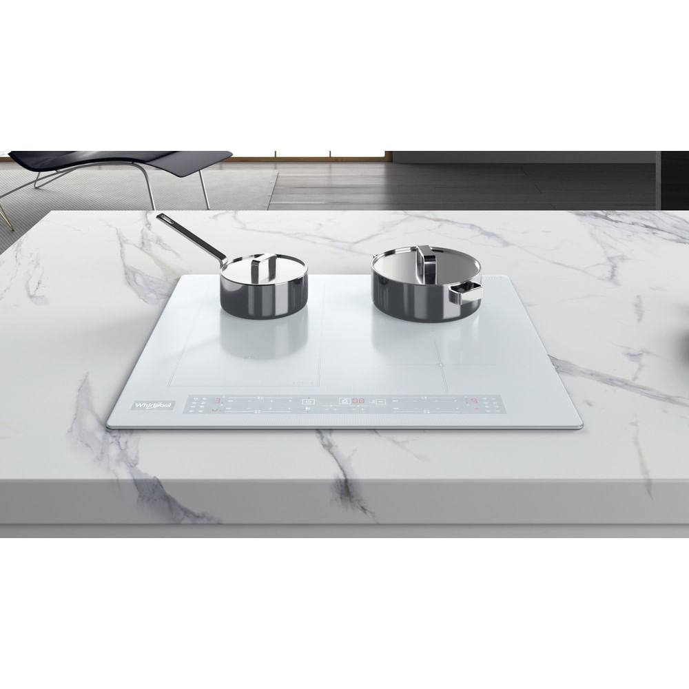 Placa de inducción blanca en encimera de mármol con dos ollas de acero inoxidable en una cocina.