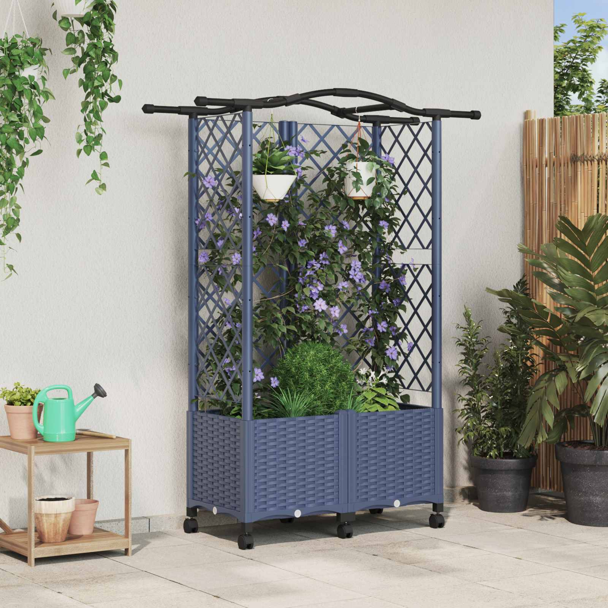 Ein blaues Rankgitter mit Pflanzkasten und hängenden Pflanzen im Topf steht auf einer Terrasse.