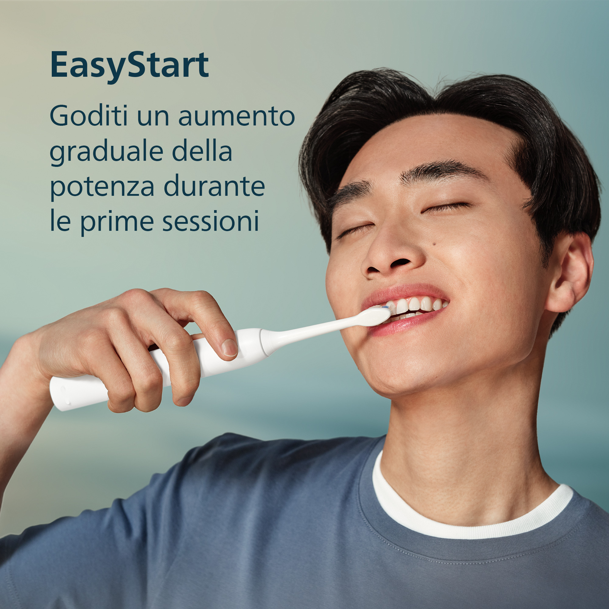 Un giovane sorride a occhi chiusi mentre si lava i denti con uno spazzolino elettrico.