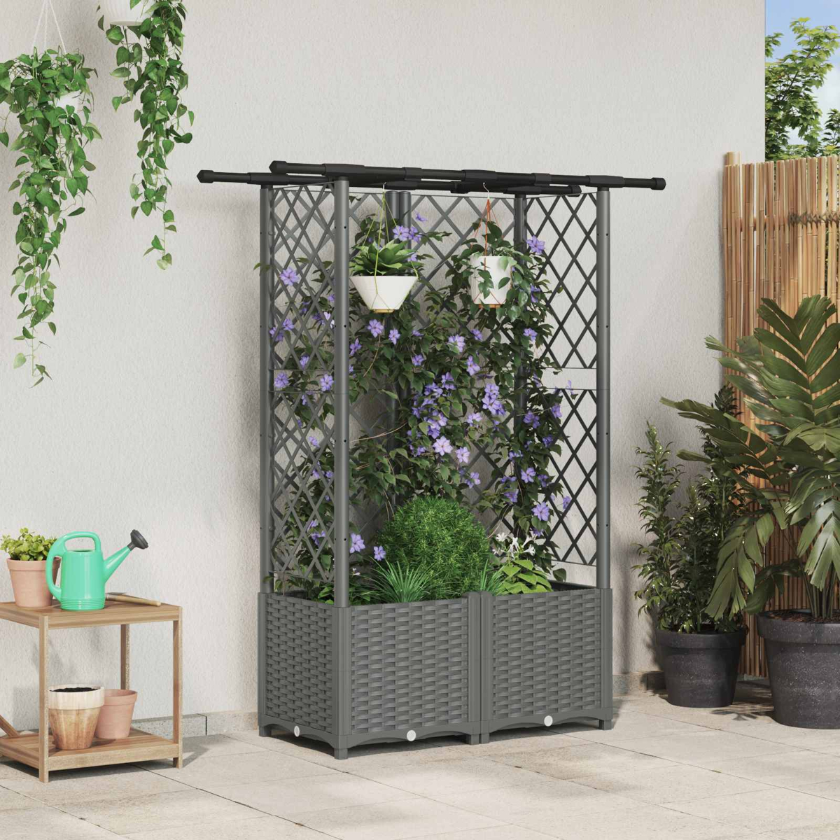 Graues Rankgitter mit Pflanzkasten, bewachsen mit lila Blumen, stehend auf einer Terrasse.