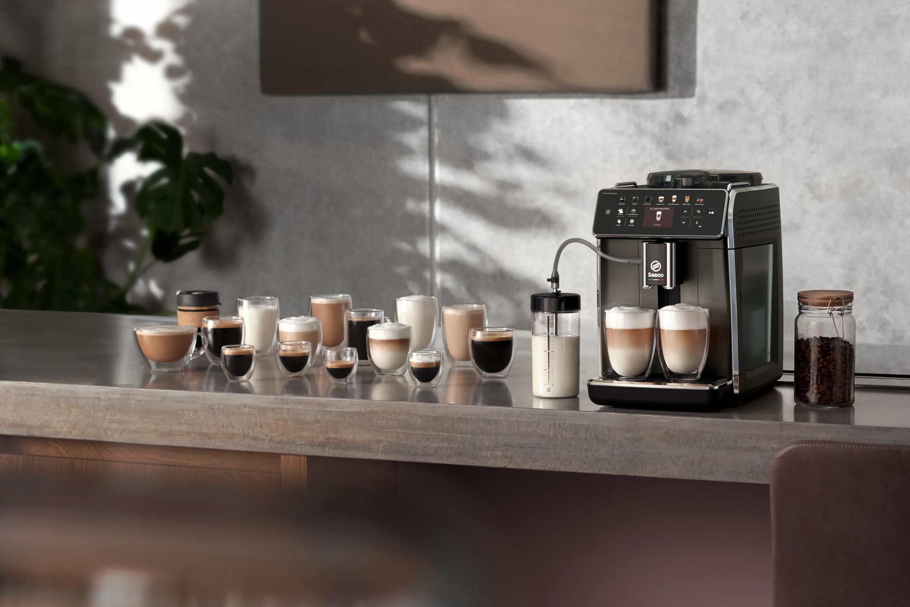 Moderna macchina da caffè su un bancone con molte tazzine di caffè piene e un contenitore del latte accanto.