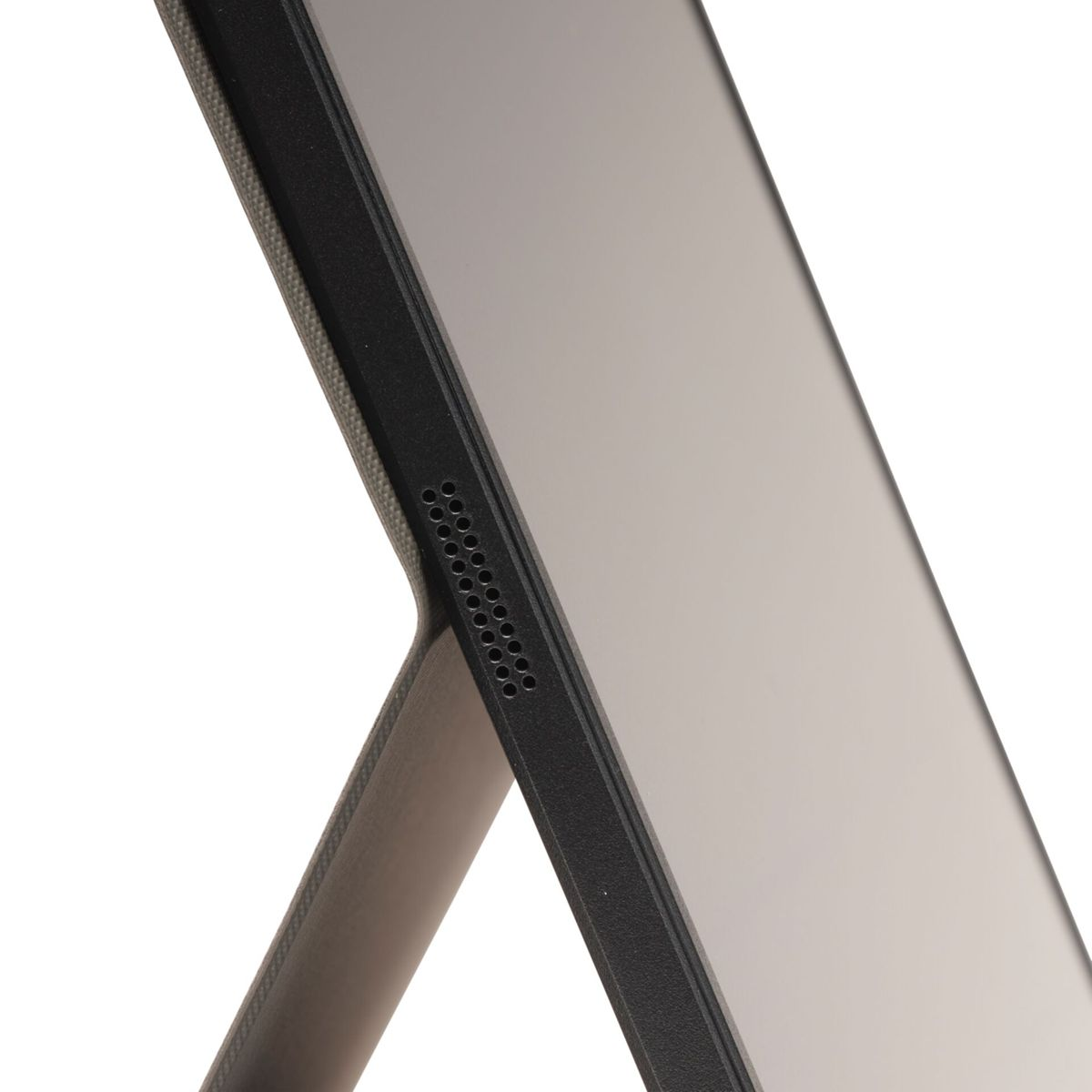 Nahaufnahme der schwarzen Kante eines Tablets oder Monitors mit einem Lautsprechergitter, gegen einen weißen Hintergrund.