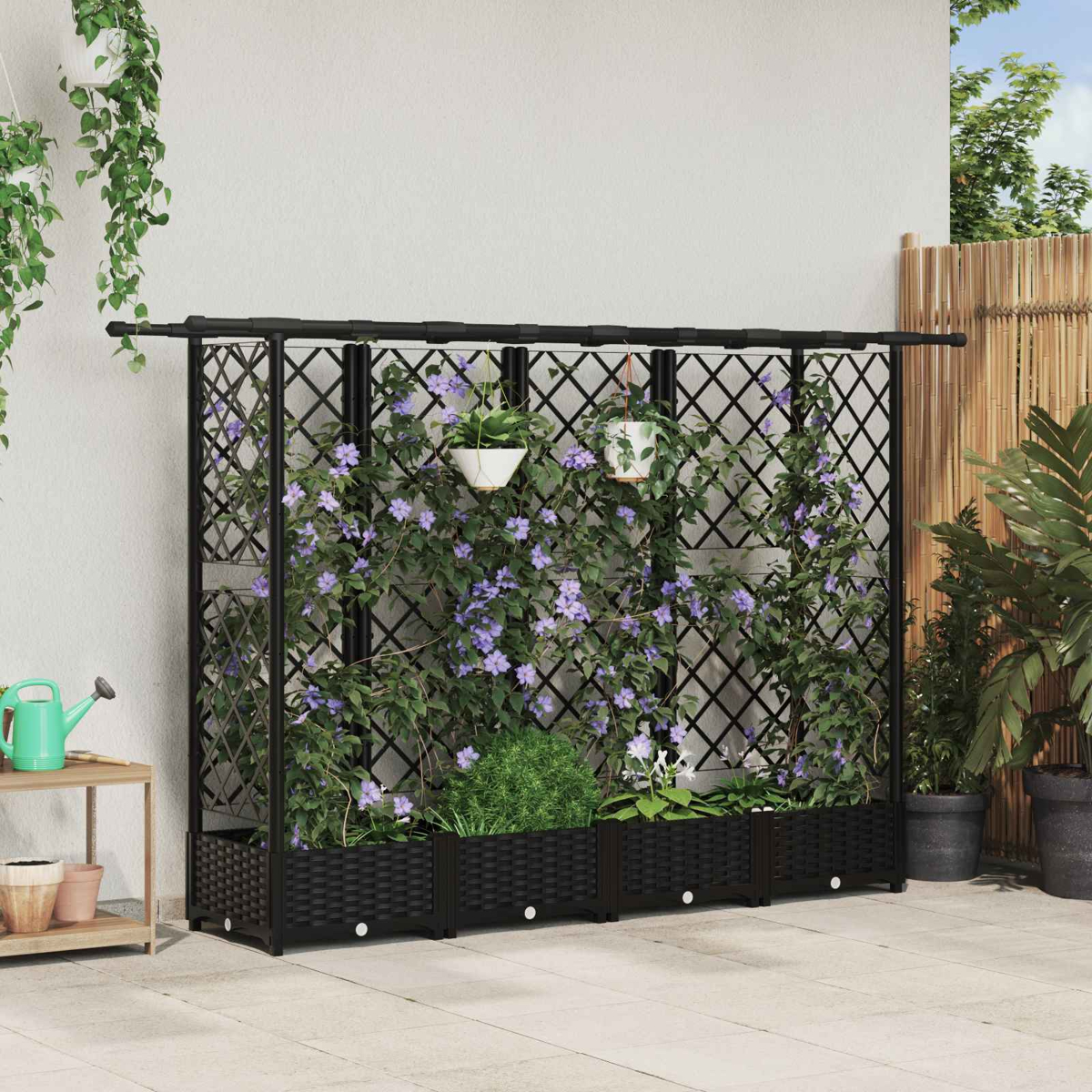 Ein schwarzes Spalier mit Pflanzkübeln und Kletterpflanzen mit lila Blüten steht auf einer Terrasse an einer Wand.