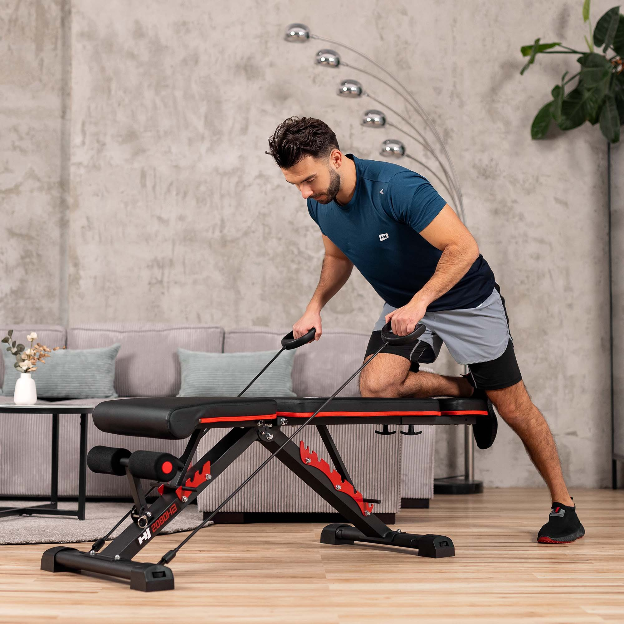 Ein Mann in Sportkleidung trainiert im Wohnzimmer auf einer multifunktionalen Trainingsbank.