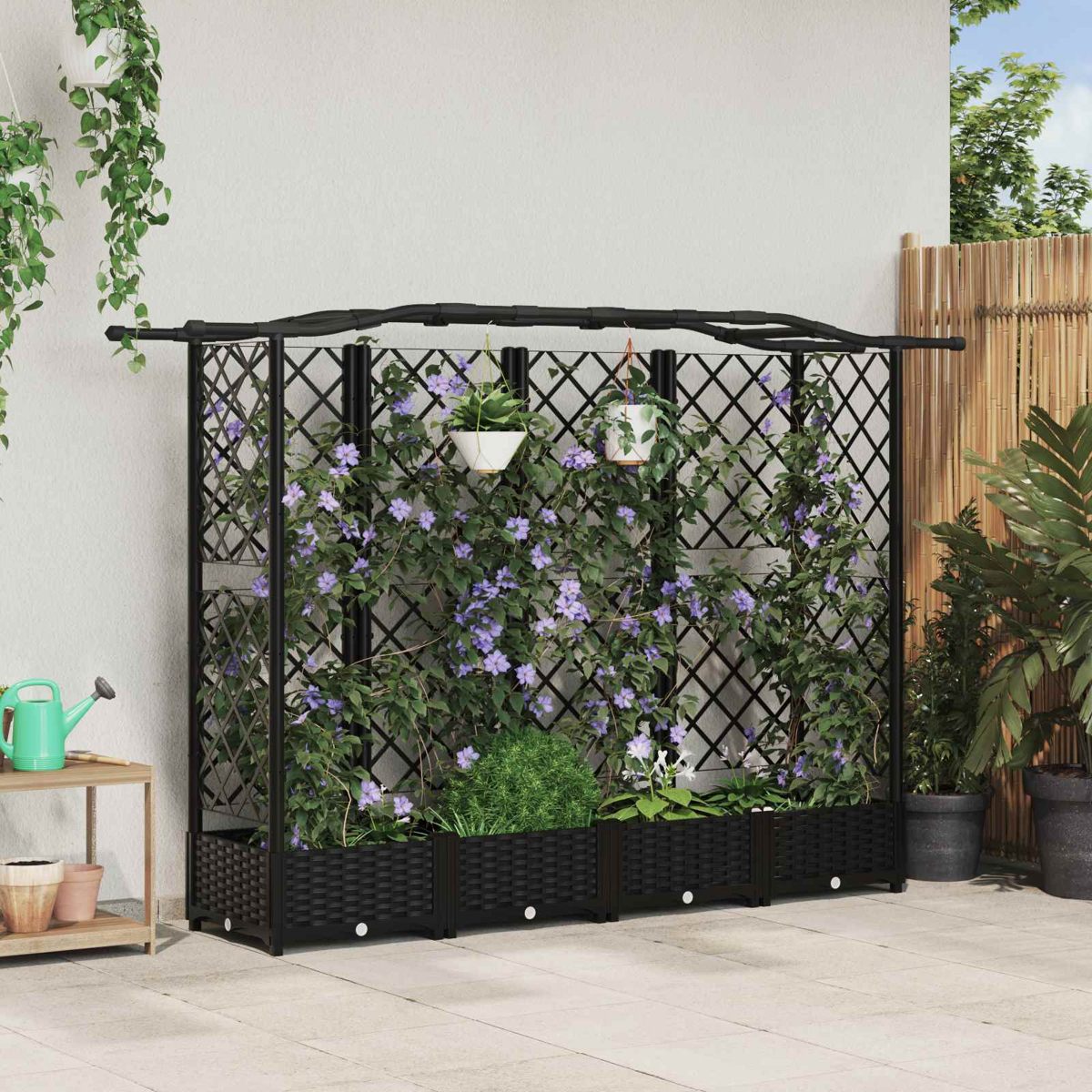 Ein schwarzes Gartenspaliers aus Metall mit integrierten Pflanzkästen und Kletterpflanzen mit lila Blüten an einer Wand.