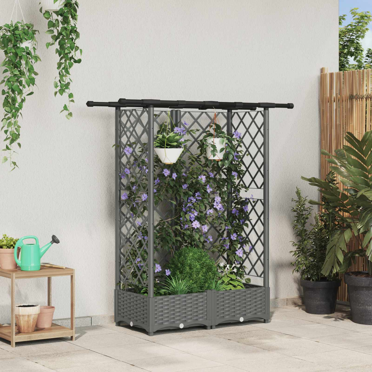 Ein graues Rankgitter mit violetten Kletterpflanzen und integrierten Pflanzkästen auf einer Terrasse.