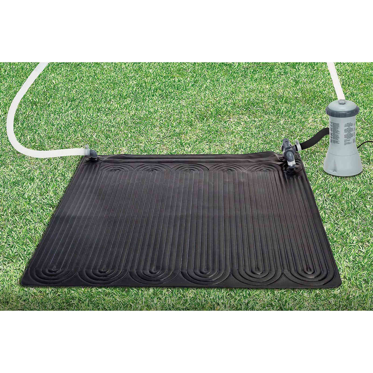 Eine schwarze Solarmatte liegt auf grünem Gras, verbunden mit weißen Schläuchen und einer Pumpe.