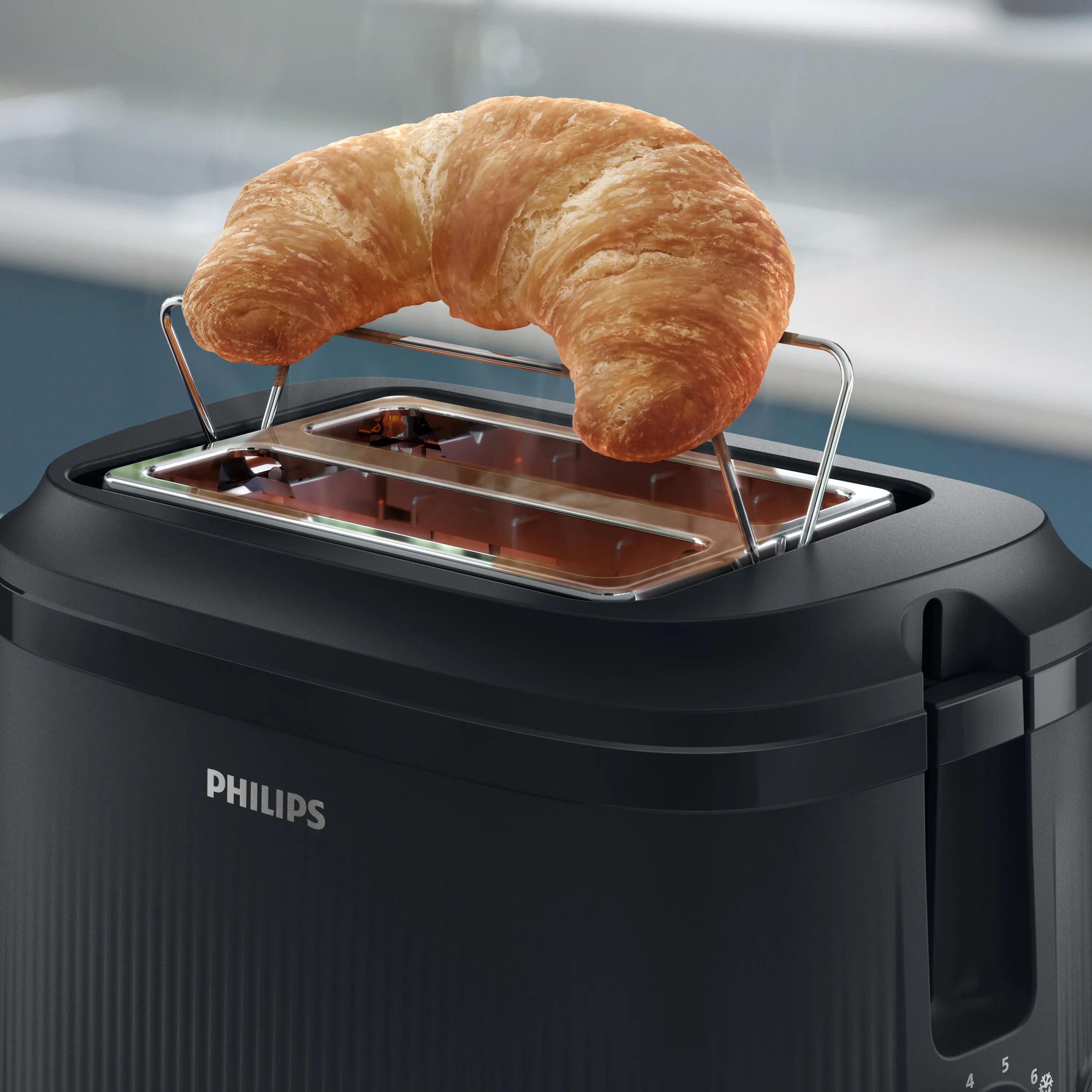 Un cornetto dorato poggia sulla griglia scalda brioche di un tostapane nero Philips in una cucina.