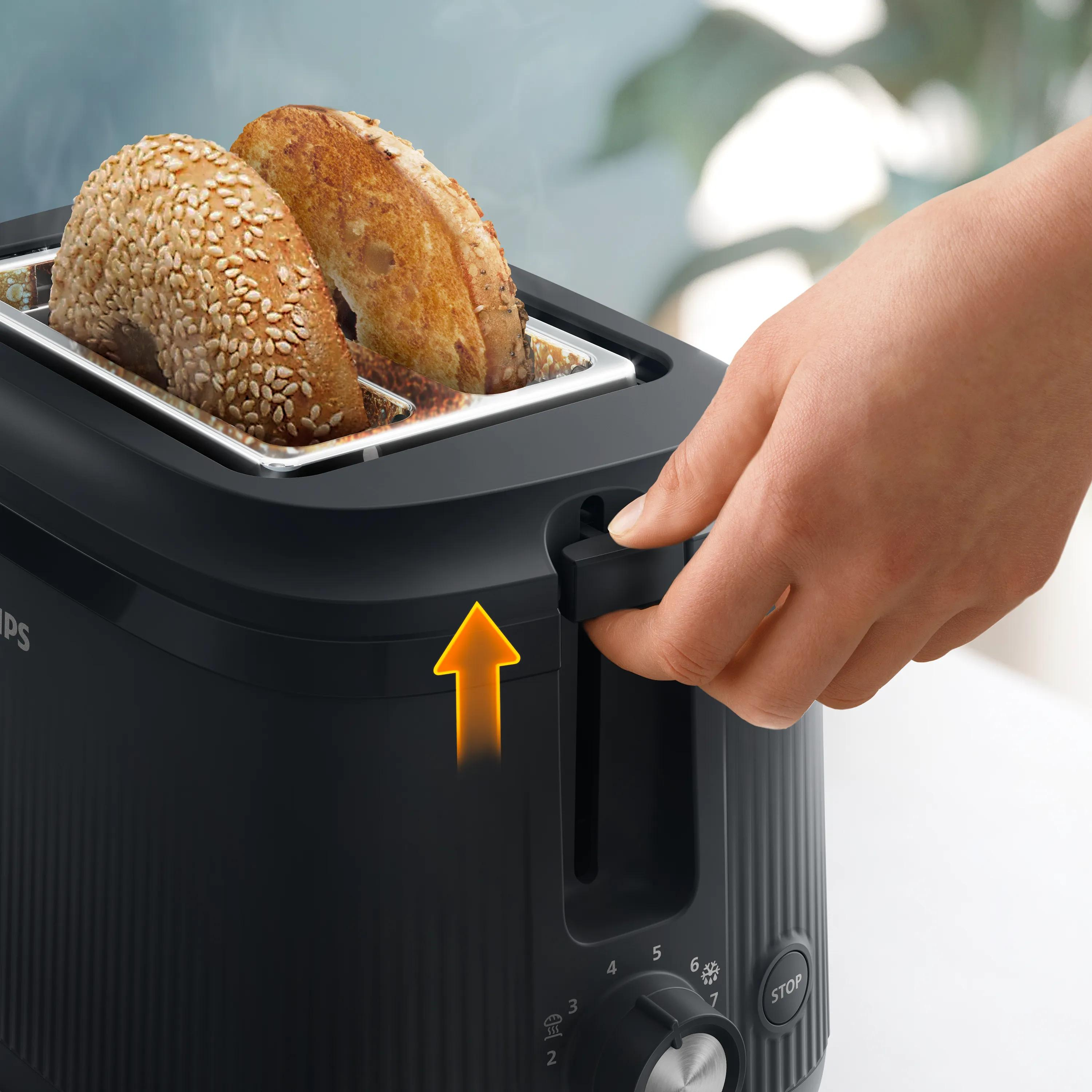 Una mano solleva due metà di bagel calde da un tostapane nero.