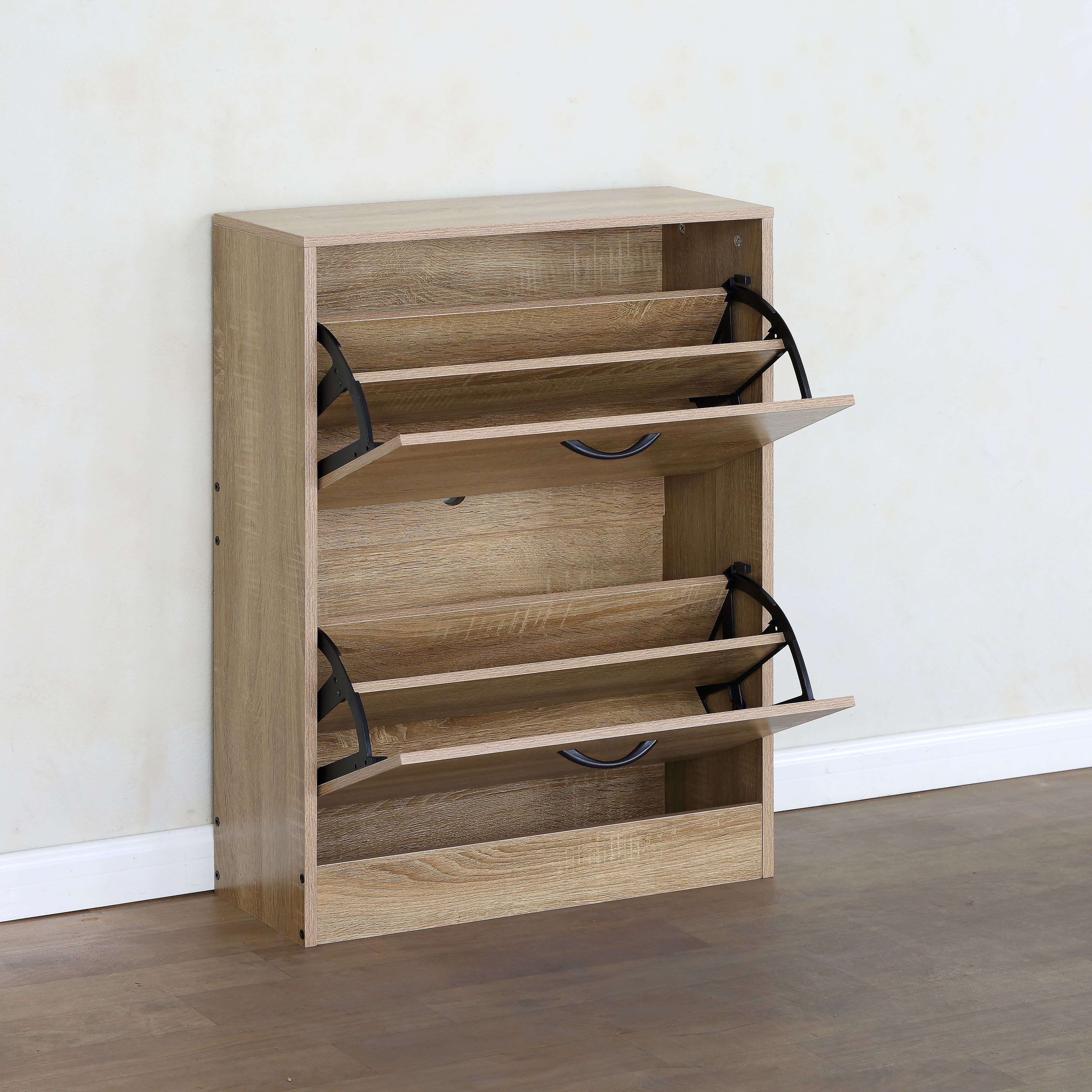 Un zapatero de madera con dos compartimentos abatibles abiertos sobre un suelo de madera oscura y pared blanca.